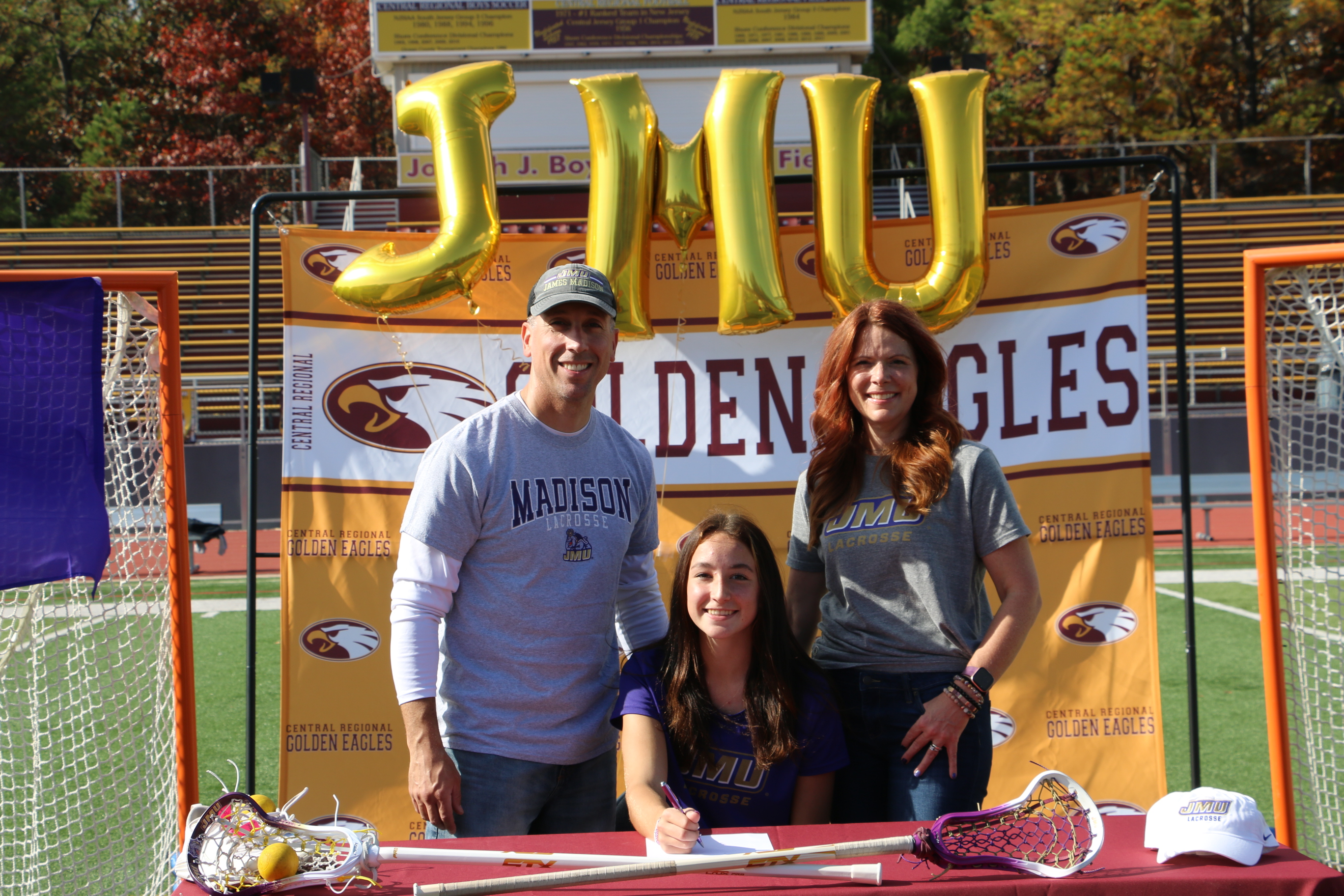 Hannah Lewis (center) and parents as she signs her National Letter of Intent to play lacrosse at James Madison University.