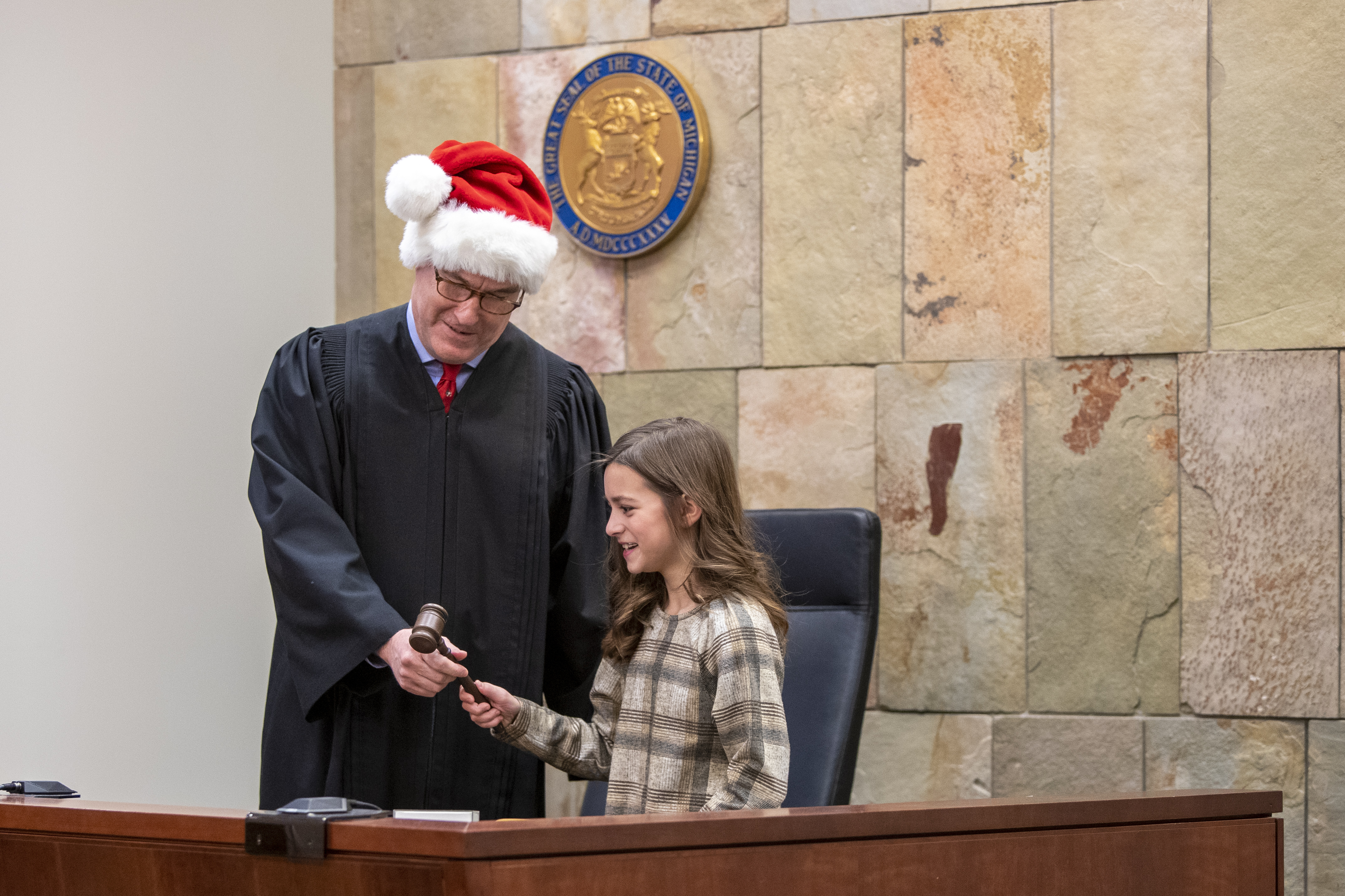 Judge T.J. Ackert lets Corryn Myers, 10, use his gavel  during Adoption Day at the Kent County Courthouse in Grand Rapids on Thursday, Dec. 8, 2022. Corryn’s parents, Tammy and Jordan Myers, are the biological parents of 1-year-old twins Eames and Ellison. Lauren Vermilye, a surrogate, gave birth to the twins after Tammy went through breast cancer treatment and has no claim to the babies. The Myers family was able to adopt the twins after convincing the court system to grant them custody. (Cory Morse | MLive.com)