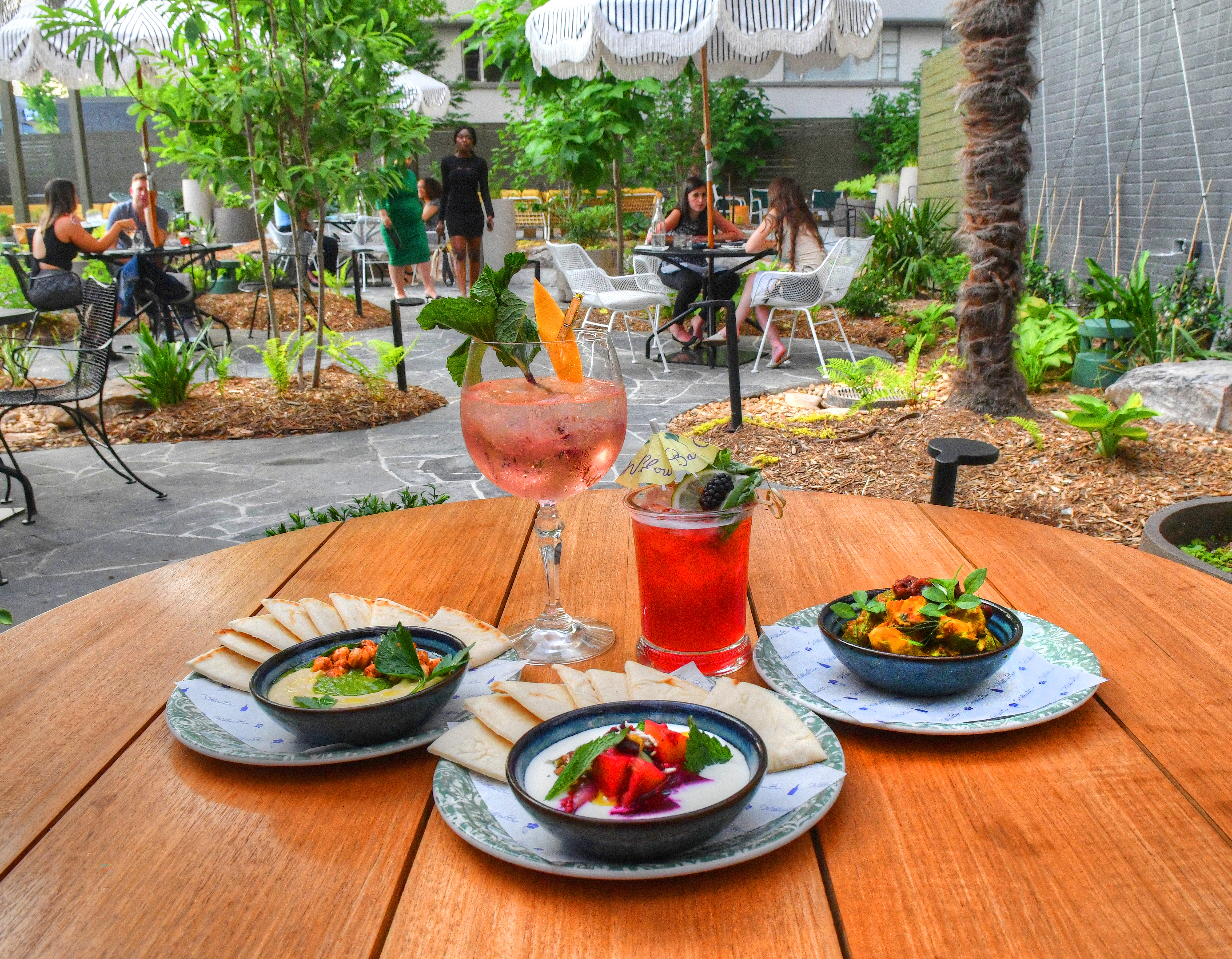 Among the offerings at Willow Bar at Kimpton Sylvan Hotel are, clockwise from top left: the Cyprus gin and tonic, Willow cocktail, charred cauliflower and cucumber avocado, beets and feta, and hummus. Chris Hunt for The Atlanta Journal-Constitution