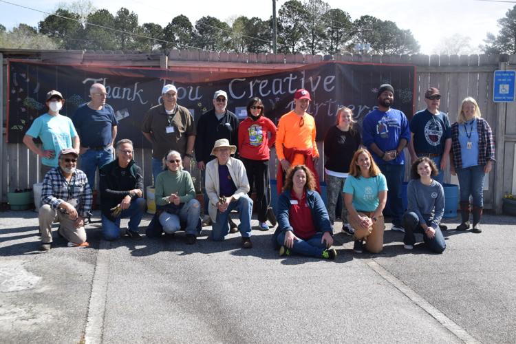 Special needs clients from Creative Enterprises join the not-for-profit staff as well as Food Well Alliance officials and other volunteers for a photo after planting an orchard at the Lawrenceville-based Creative Enterprises. (Courtesy of Curt Yeomans)