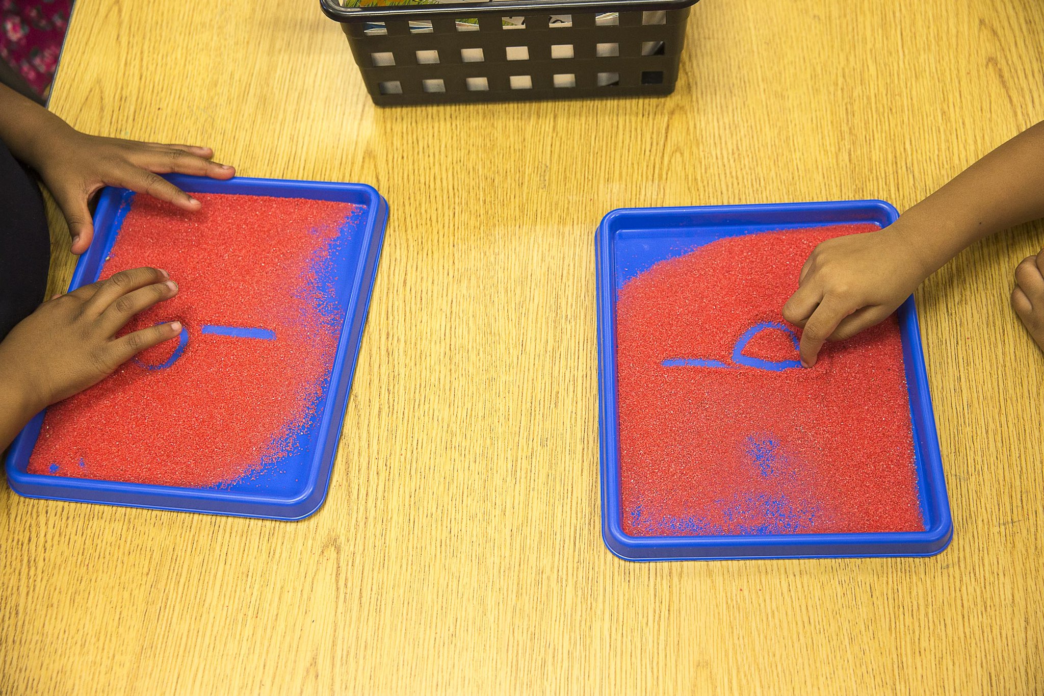 Kindergartners draw the letter “b” in a tray of sand while learning phonics at Benteen Elementary School in Atlanta.