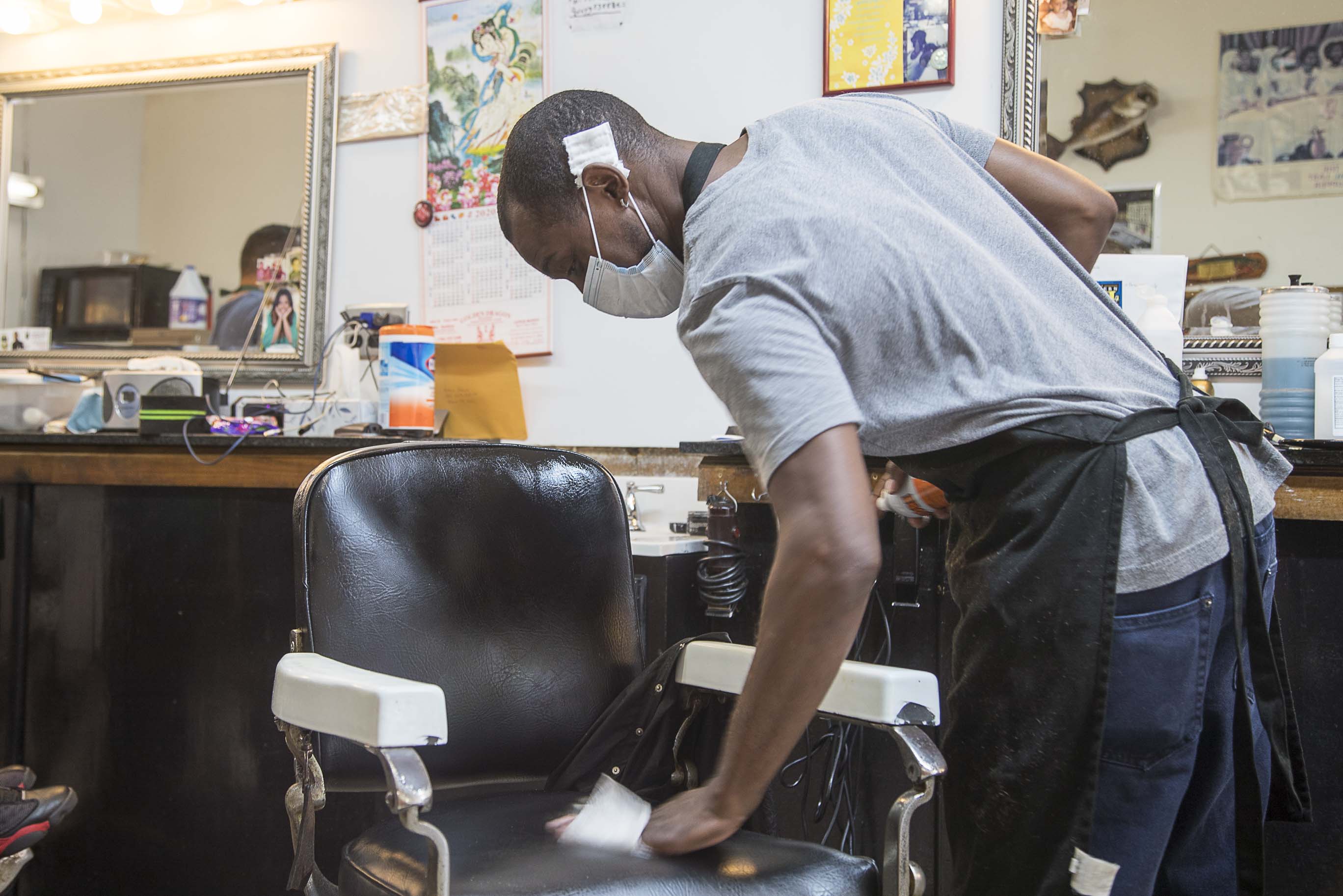Athens, Georgia - Wearing a mask, Tony Brown, barber at Brown's Barber Shop, uses a disinfectant wipe to sanitize his chair after servicing a client at the shop in downtown Athens, Friday, April 24, 2020. The family owned small business reopened on Friday, after receiving clearance from Gov. Brian Kemp. (ALYSSA POINTER / ALYSSA.POINTER@AJC.COM)