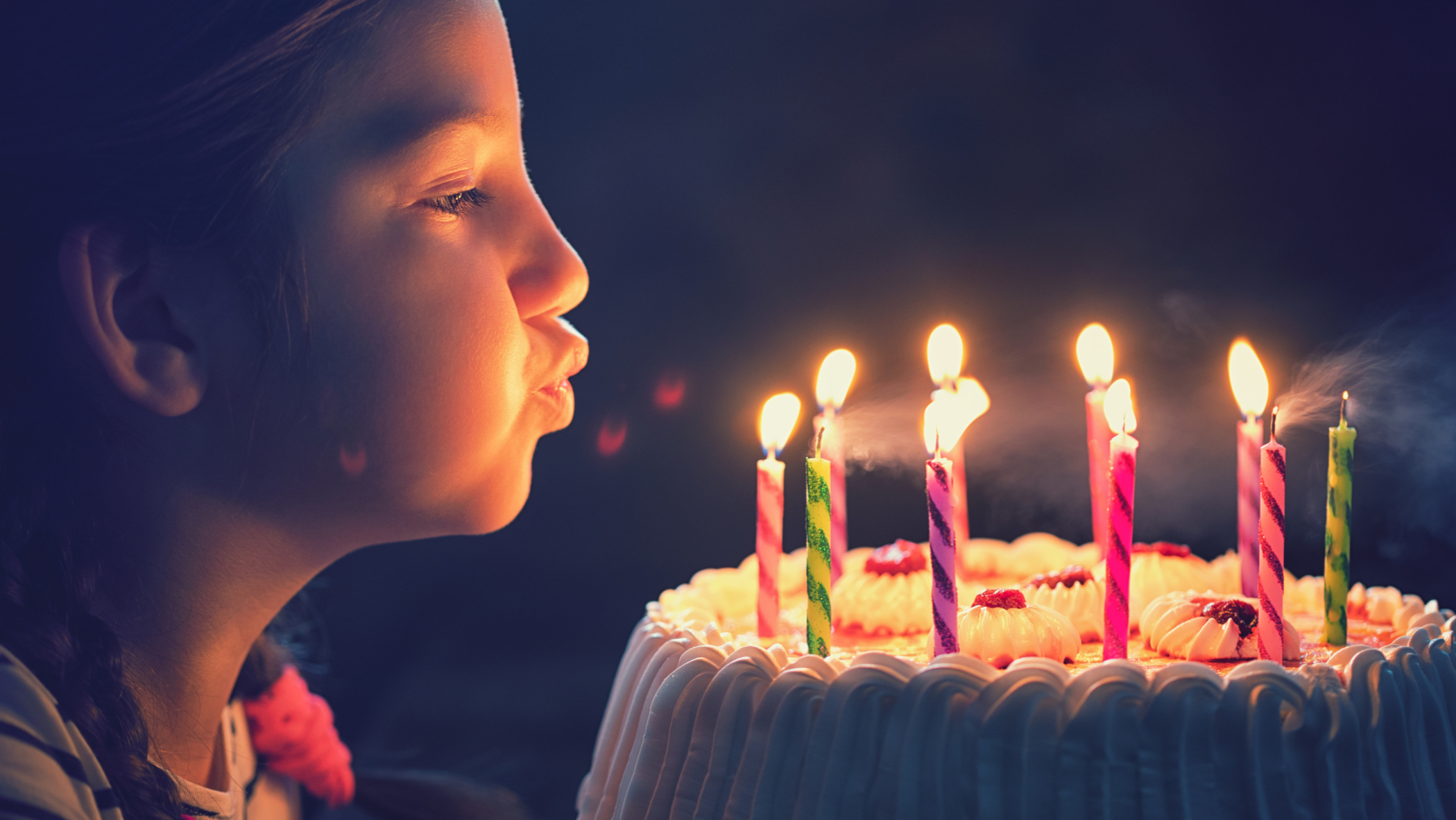 Boy ready to blow out candles on birthday cake against blue backdrop. stock  photo - OFFSET