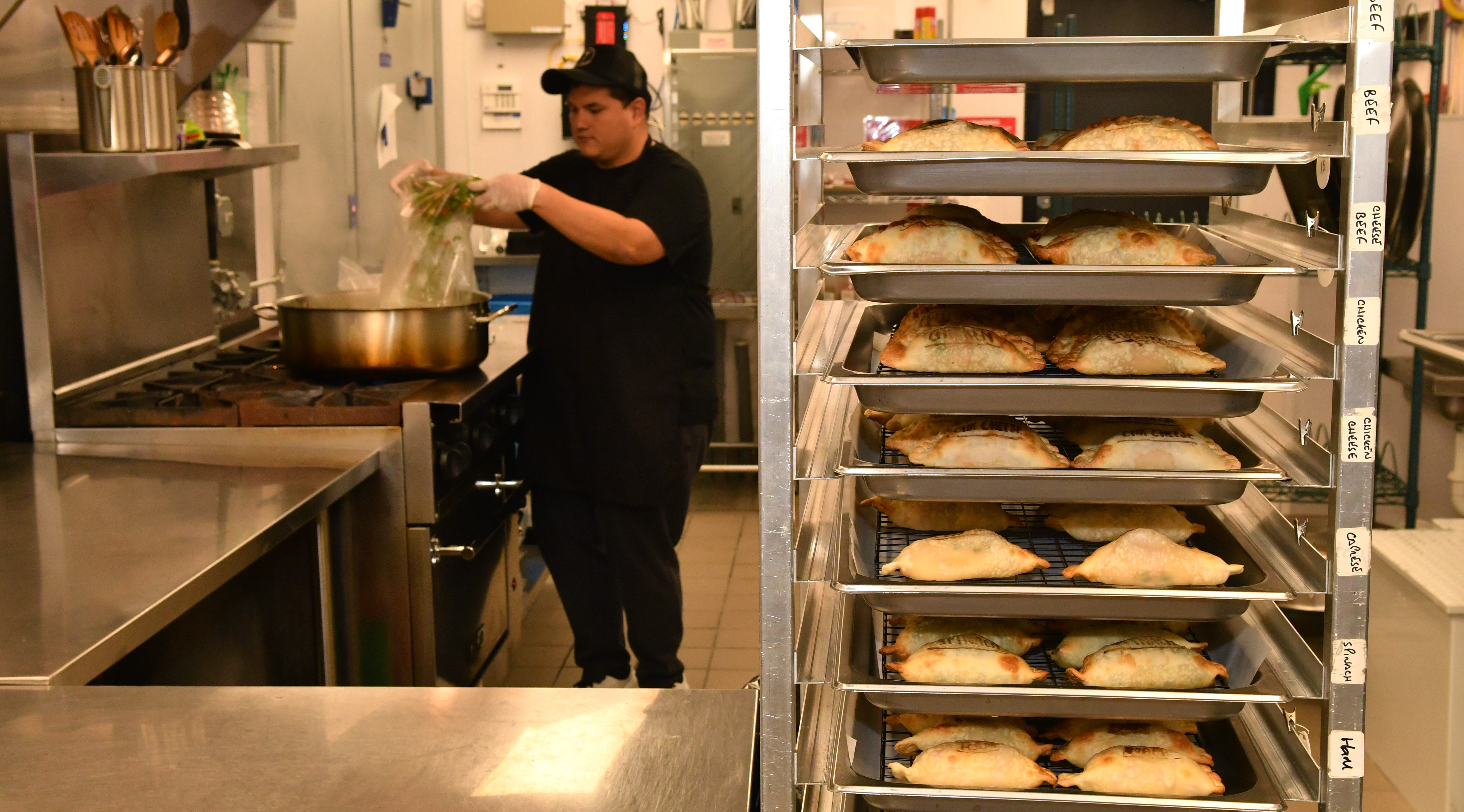Vers gebakken empanadas die afkoelen terwijl vullende ingrediënten koken op de achtergrond van de keuken van Belén de la Cruz Empanadas & Pastries.  (Chris Hunt voor The Atlanta Journal-Constitution)