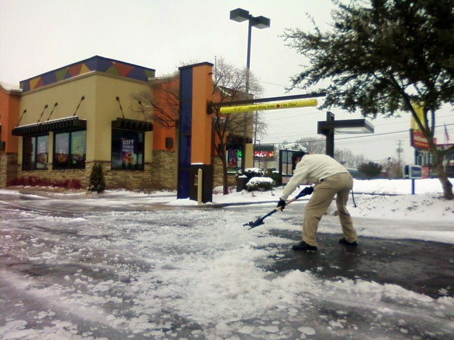 Matt Lindner, manager of the Taco Bell near the intersection of Johnson's Ferry and Lower Roswell roads in Cobb, shovels ice and slush off the parking lot in this Jan. 11, 2011 file photo. "Businesswise, it's a curse," he said of the storm. "It's affecting a lot of people's business, and their money."
