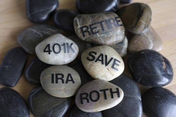 Smooth stones with words written on them such as retire, 401k, IRA, Save, and Roth.