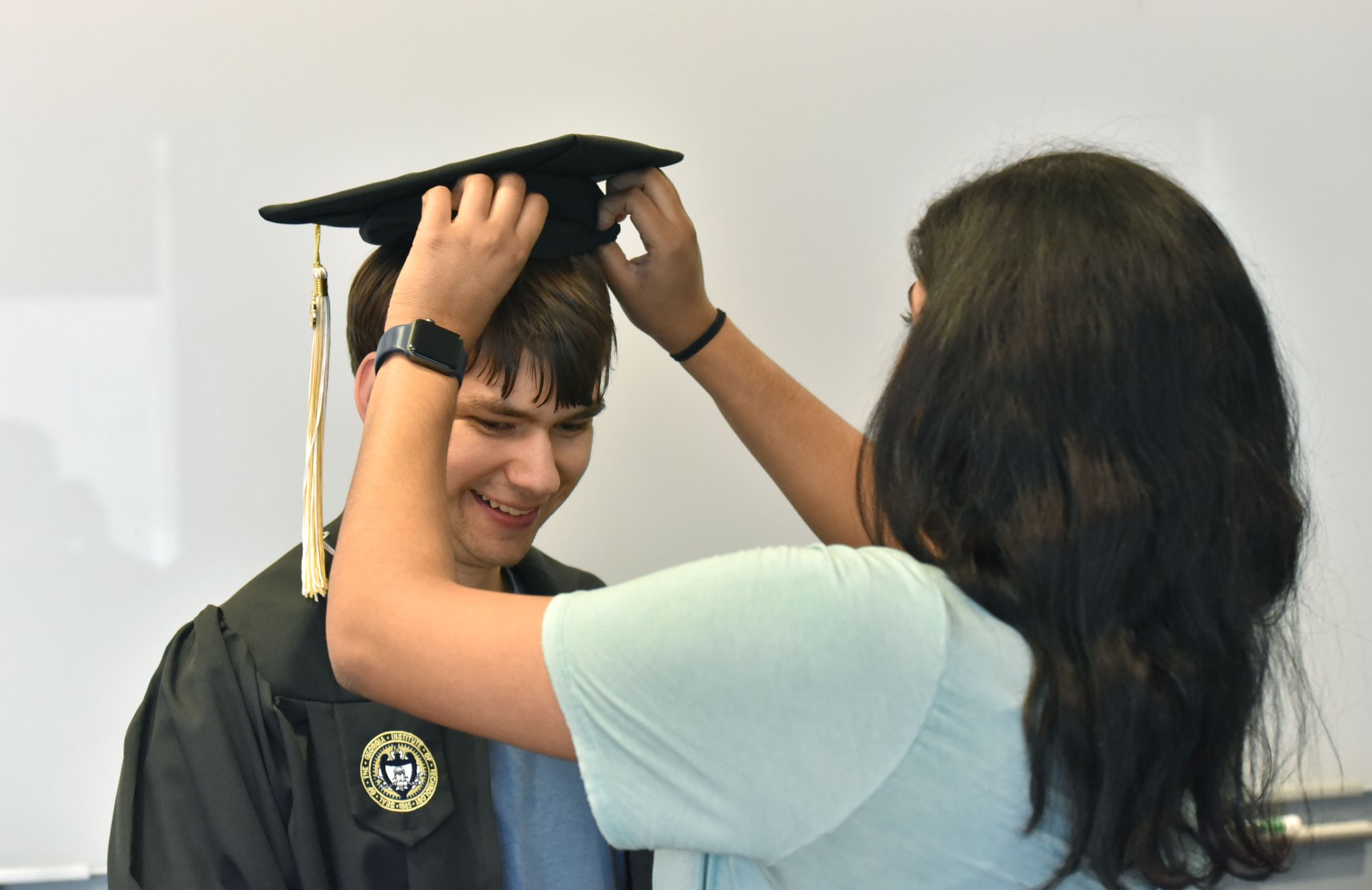 Kurt Vogel tries on his cap and gown as Ankita Raghupathy, right, teaching assistant, helps during a graduation rehearsal of the EXCEL program for students with intellectual disabilities at Georgia Tech’s Scheller College of Business.