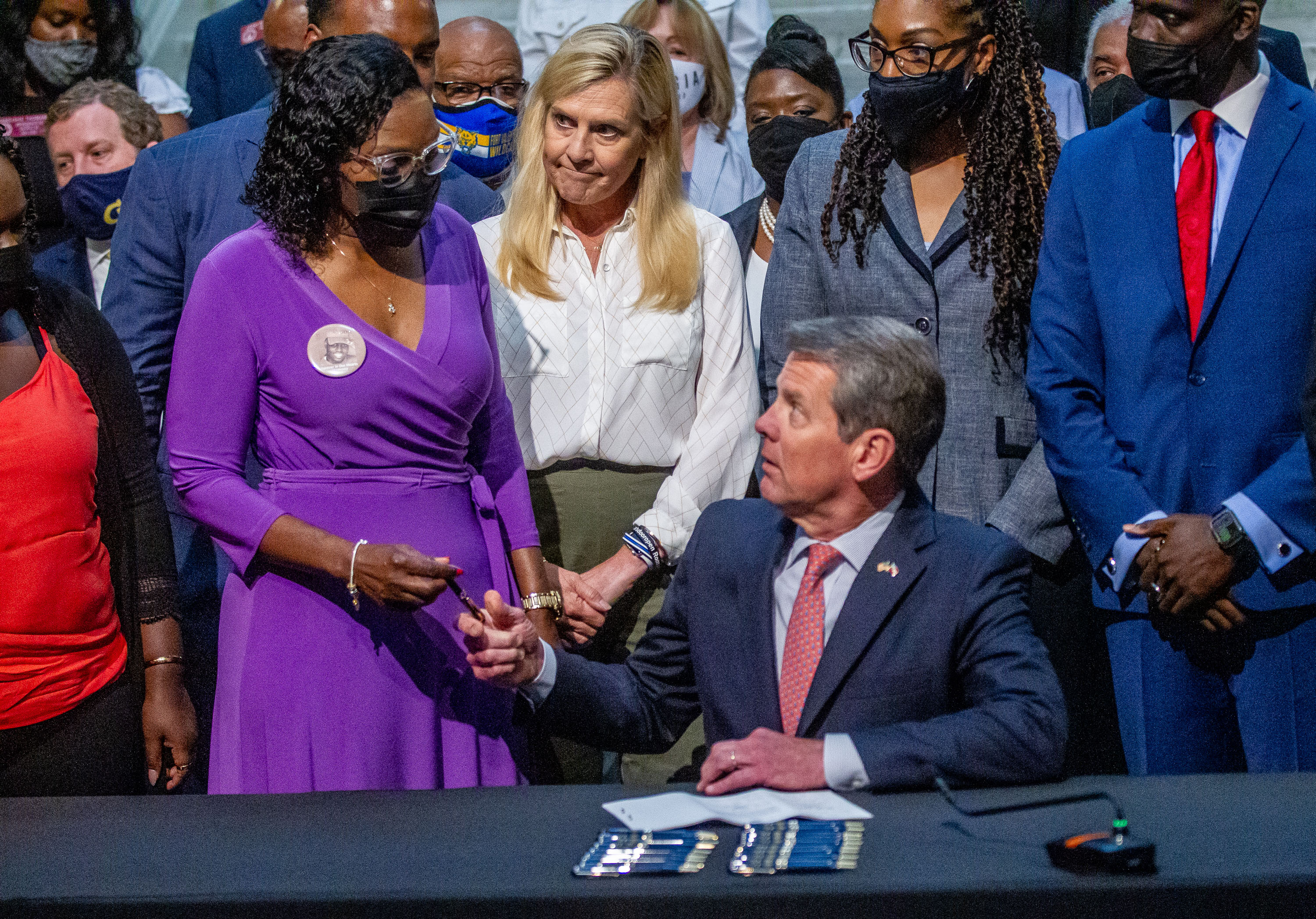 Gov. Brian Kemp hands Wanda Cooper-Jones (left) a pen as first lady Marty Kemp watches after Kemp signed HB 479, which repeals Georgia's citizen's arrest law at the State Capitol on May 10, 2021. (STEVE SCHAEFER for the Atlanta Journal-Constitution)