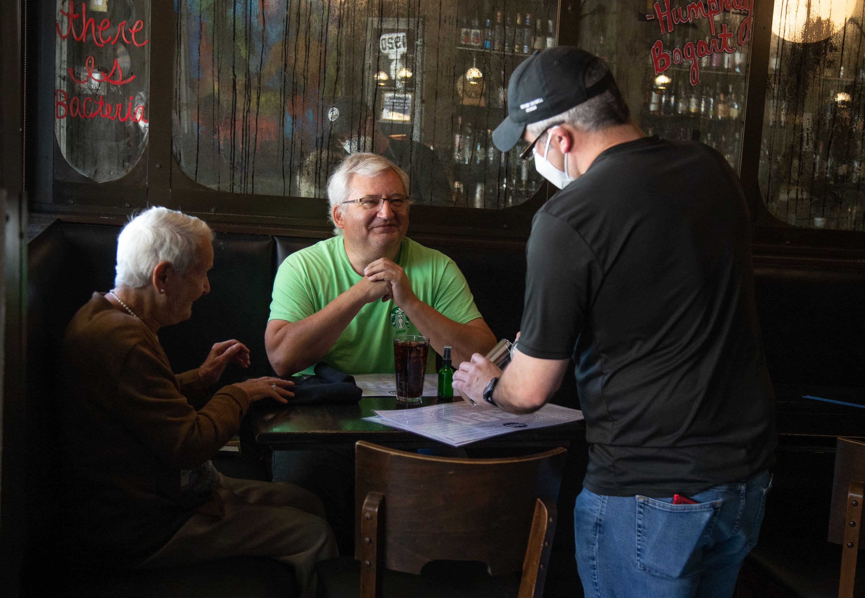 1920 Tavern employee Shane Goode (R) delivers drinks to Bart Van Linden and his mother, Sabine Van Linden, at the Roswell restaurant Monday, April 27, 2020. STEVE SCHAEFER / SPECIAL TO THE AJC