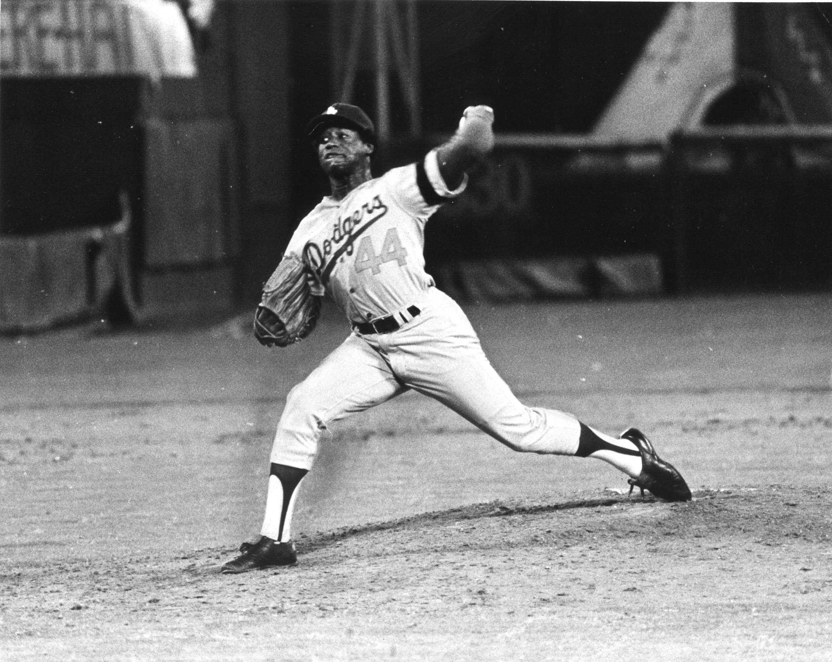 FILE - In this April 8, 1974, file photo, Hank Aaron tips his hat to fans  and teammates, including Dusty Baker (12, wearing batting helmet at center  right), greeting him at home