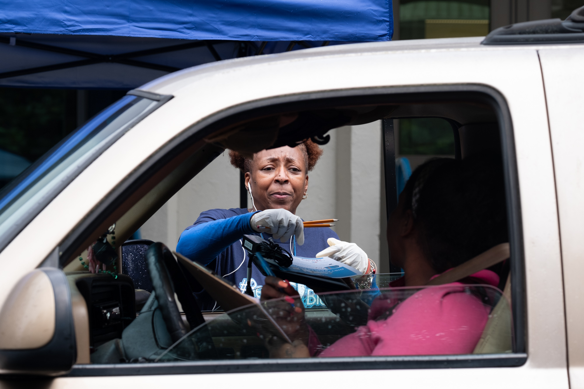 Janice Alexander, a kindergarten parapro at Harper-Archer Elementary School, hands a computer to a parent who came to the school Tuesday afternoon March 24, 2020. The school was issuing devices to students so they could continue studying during the coronavirus pandemic.