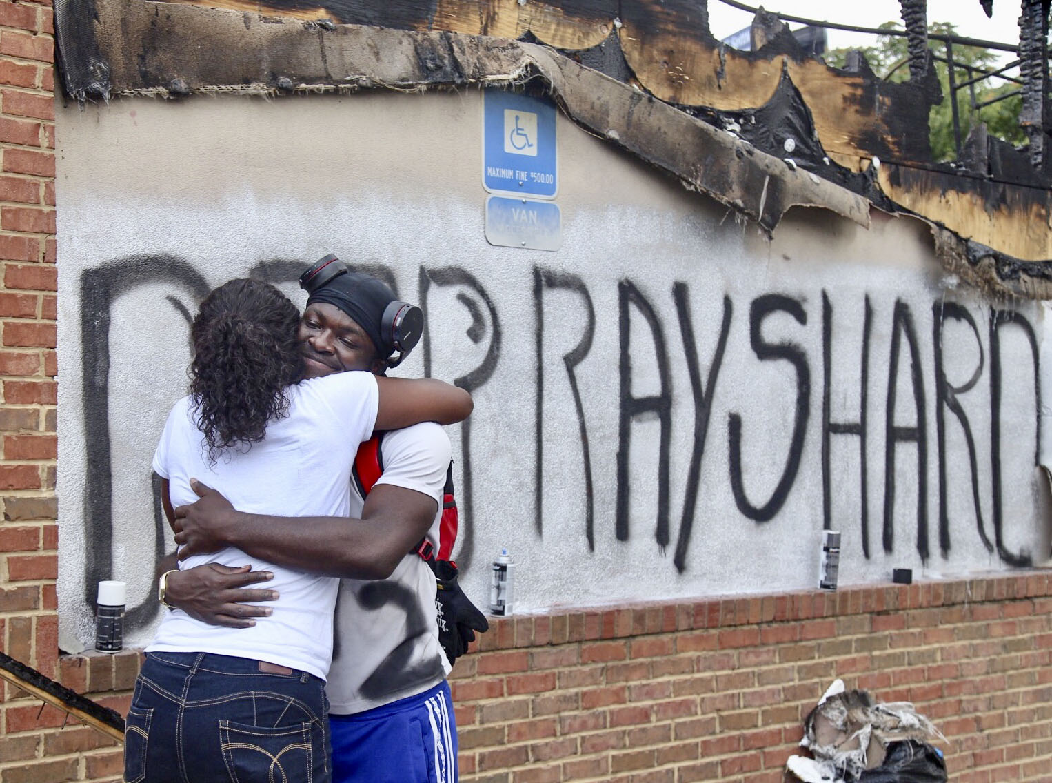 Eva Snow and Joseth Jett hug after Jett spray-painted over the top of graffiti from the night before and painted RIP Rayshard. People began showing up at Wendy's on University Avenue Sunday morning, June 14, 2020. Some helped with cleanup, some came to look, and some began placing flowers and created a memorial. On Saturday, protesters set fire to the Atlanta Wendy's where Rayshard Brooks, a 27-year-old black man, was shot and killed by Atlanta police Friday evening during a struggle at a Wendy's drive-thru line. (Photo: Steve Schaefer for The Atlanta Journal-Constitution)