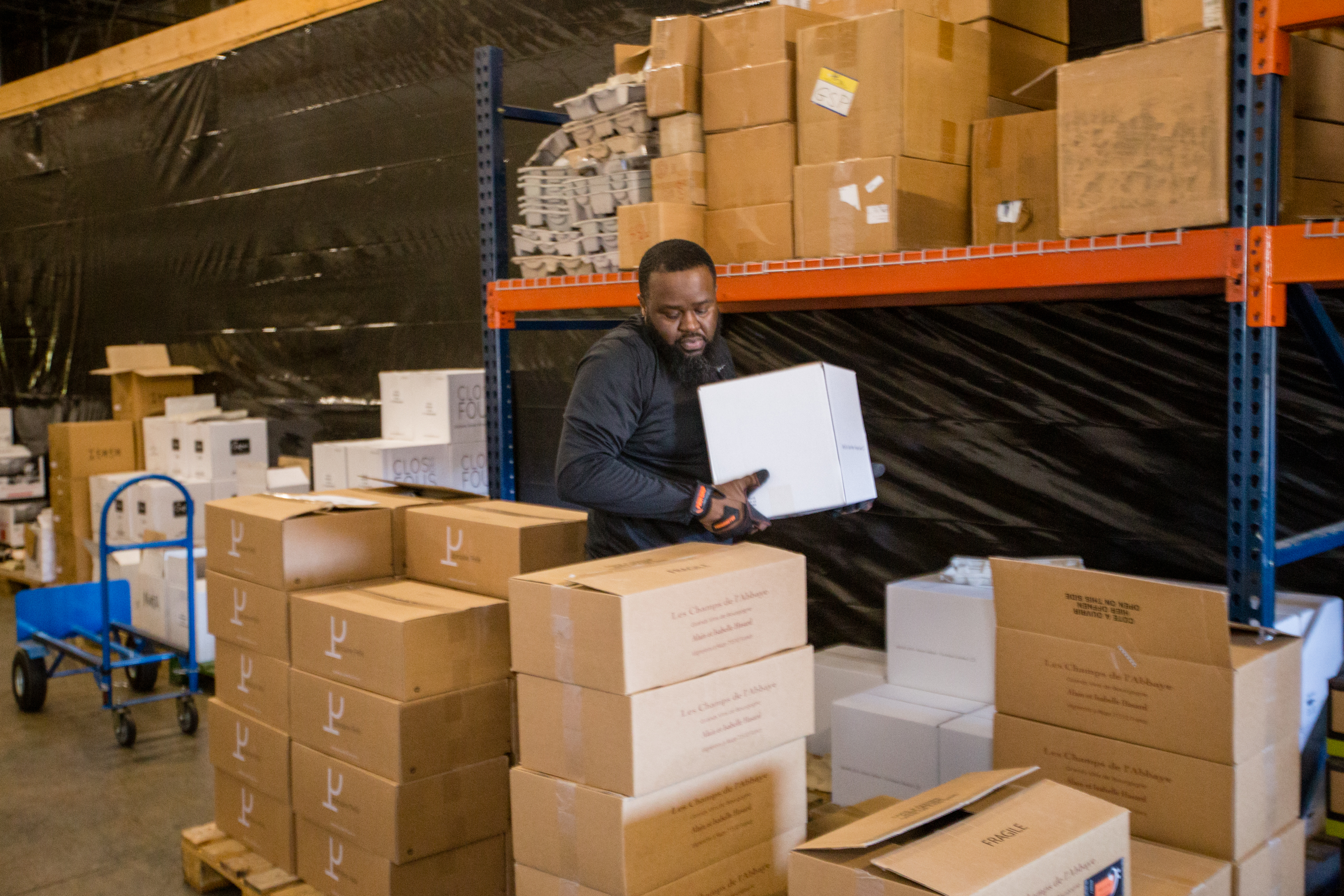 Avant Partir warehouse manager Eugene Holland works to package pallets of wine for distribution on Wednesday, March 26, 2020. Eugene usually has another person working with him in the warehouse. Avant Partir is a high-end wine distributor in Duluth, and has modified purchases and is moving much less product to restaurants and retailers in recent weeks due to the coronavirus. The business is working to keep all employees on the payroll but is cutting back hours and taking turns in the warehouse. (Jenni Girtman for the Atlanta Journal Constitution)