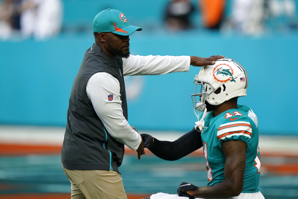 Miami Dolphins head coach Brian Flores pats the helmet of Miami wide receiver DeVante Parker (11) as he stretches during warm-ups ahead of an NFL football game against the New England Patriots, Sunday, Jan. 9, 2022, in Miami Gardens, Fla. (AP Photo/Wilfredo Lee)