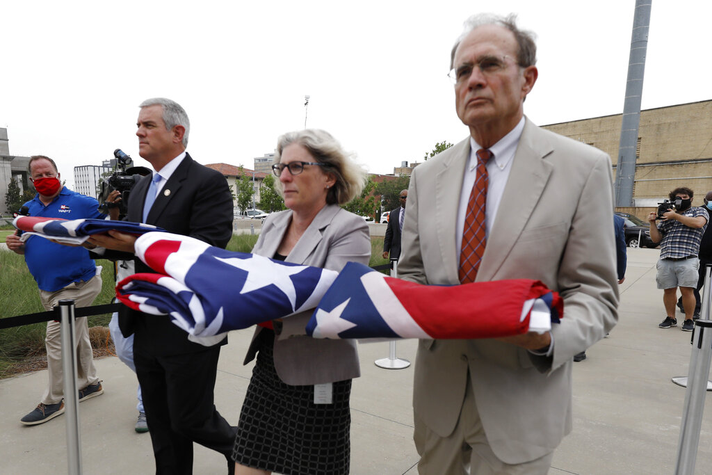 Speaker Philip Gunn, R-Clinton, left, Lt. Gov. Delbert Hosemann, right, and Mississippi Department of Archives and History Director Katherine Blount, center, carry the former Mississippi state flags to the Two Mississippi Museums during its retirement ceremony in Jackson, Miss., Wednesday, July 1, 2020. The flags had flown over the Capitol grounds during the day. The banner was the last state flag with the Confederate battle emblem on it. (AP Photo/Rogelio V. Solis)