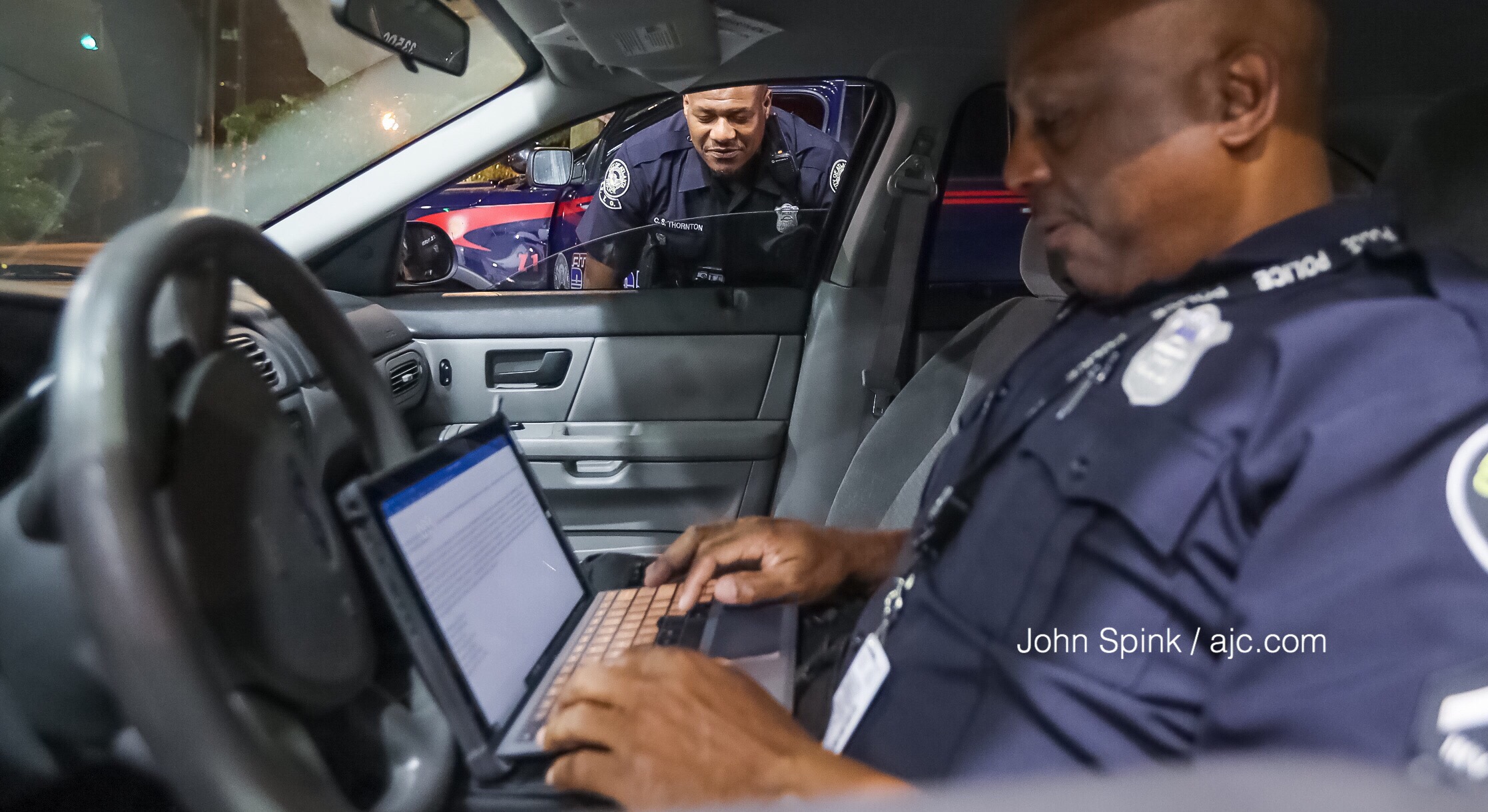 Atlanta police officers C.S. Thonton (left) and D. Terrell work on a report after a Morehouse College student was carjacked early Thursday. Police called the case "pretty heartbreaking," as the student was robbed of his transportation to a relative's funeral back home in Louisiana. JOHN SPINK / JSPINK@AJC.COM