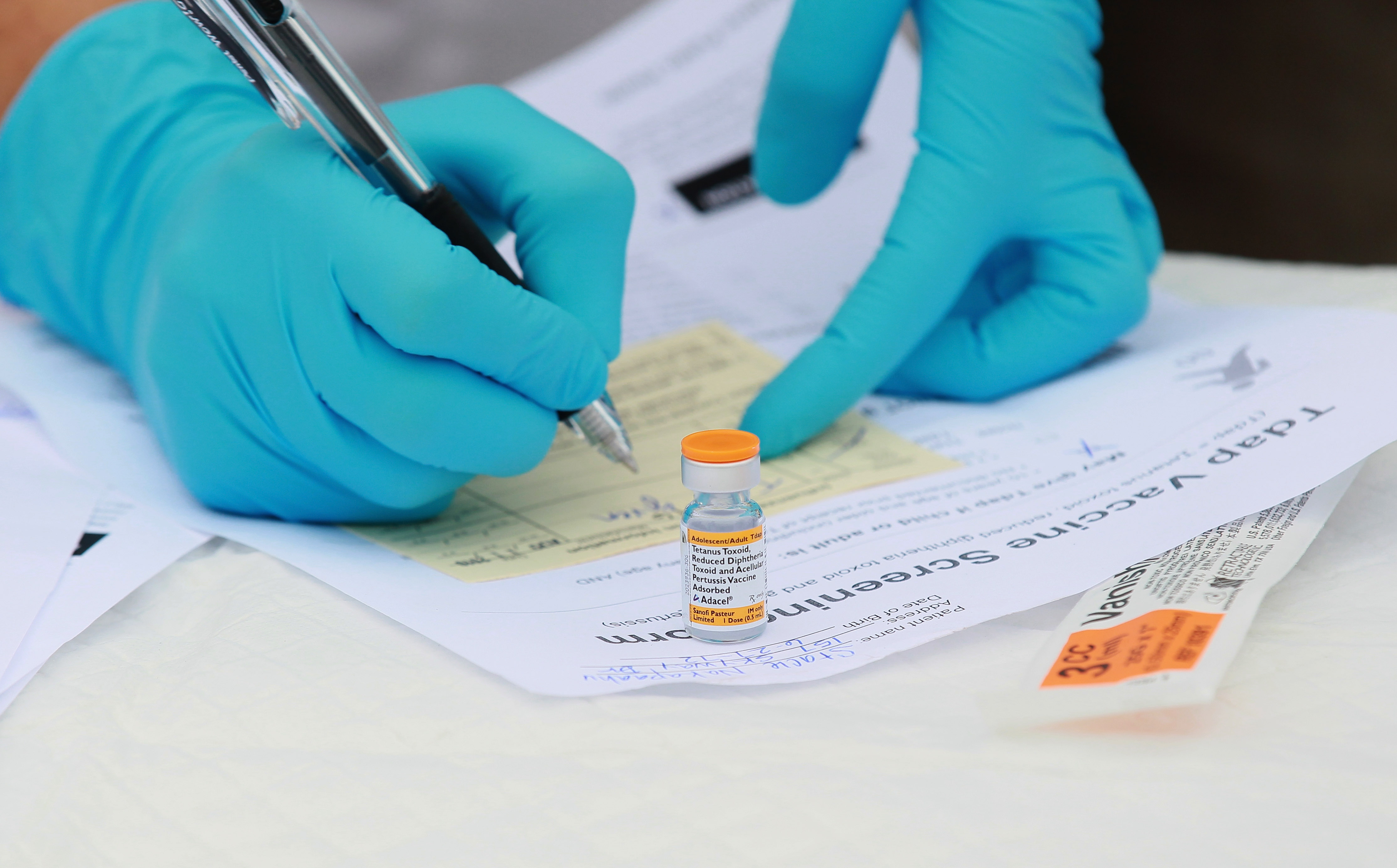In this file photo, Touro University medical student Shamis Fallah prepares paperwork before adminstering a Tdap vaccination during the Solano County health fair August 11, 2010 in Vallejo, California. (Photo by Justin Sullivan/Getty Images)