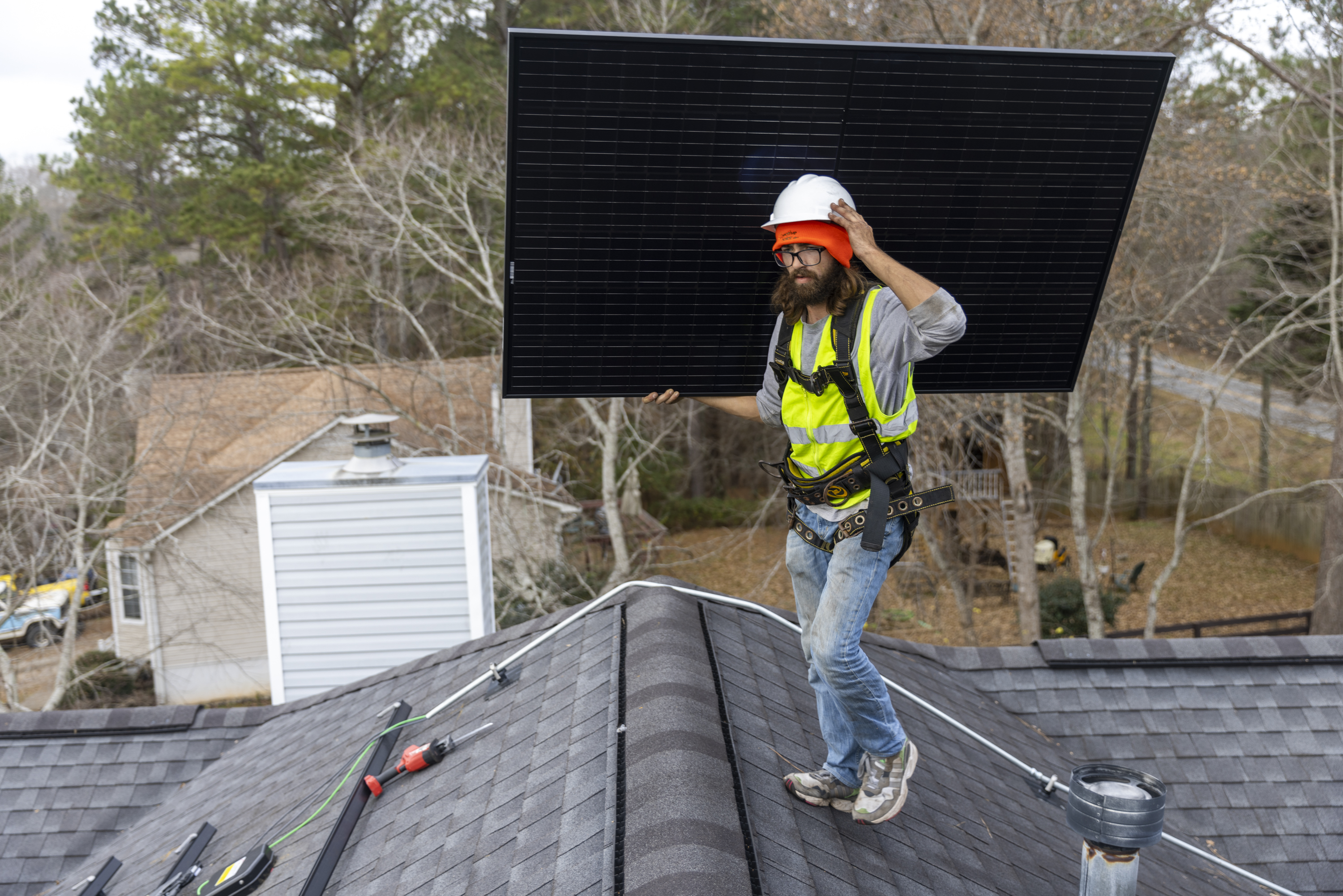 Joe McClain, an installer for Creative Solar USA, moves solar panels onto the roof of a home in Ball Ground, Georgia on December 17th, 2021.