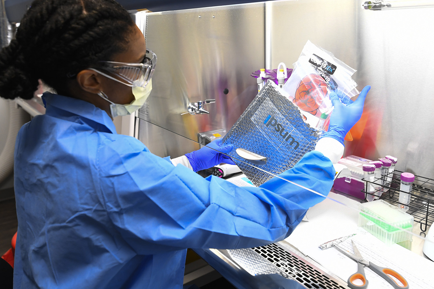 Molecular Biologist Leah Roberts gets a delivery of COVID-19 samples from a local practice ready for testing at Ipsum Diagnostics labratory on Monday, March 23, 2020. (John Amis)