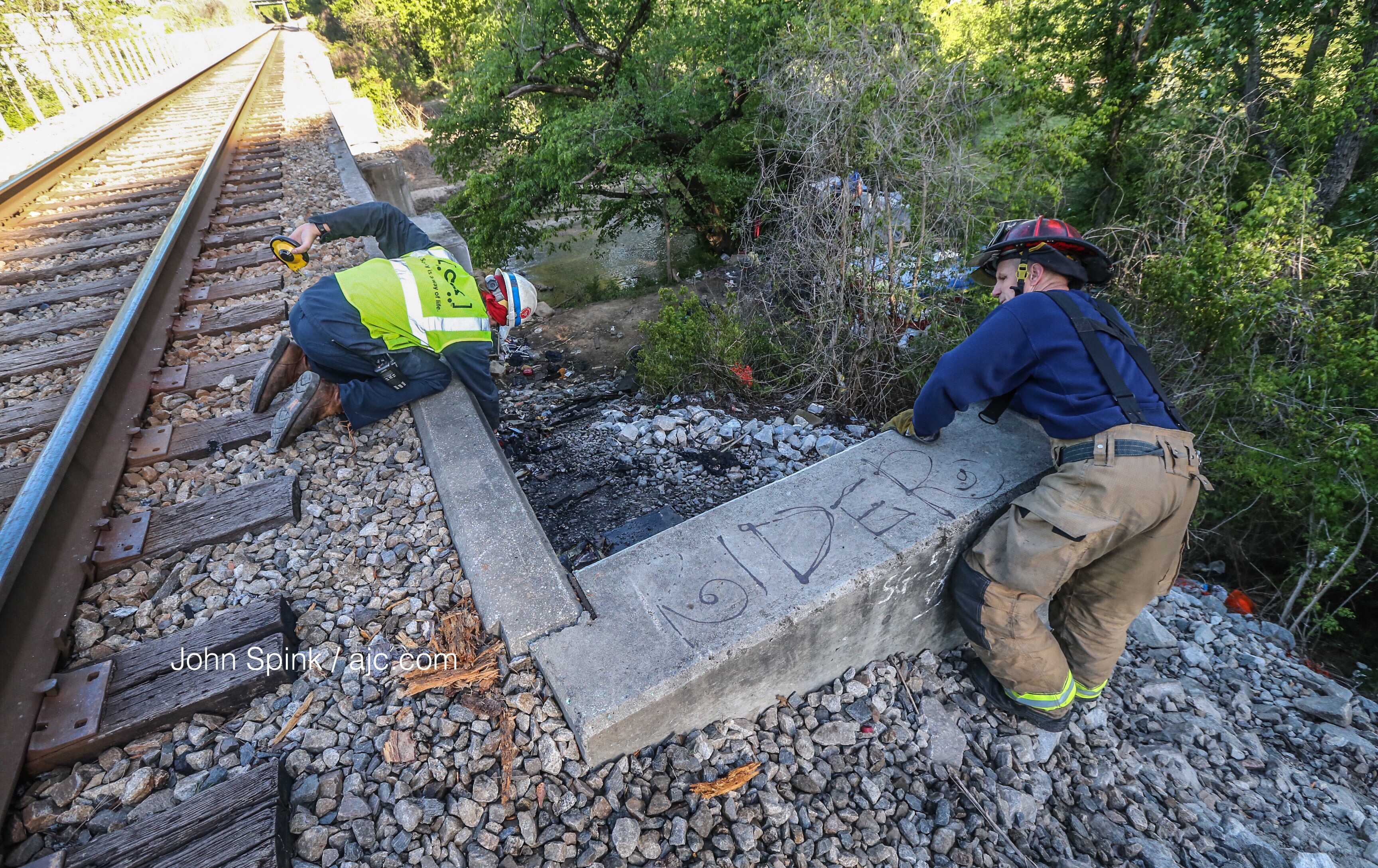 A CSX employee and Atlanta fire Capt. Eric Banaszek took measurements of the bridge after the blaze. JOHN SPINK / JSPINK@AJC.COM