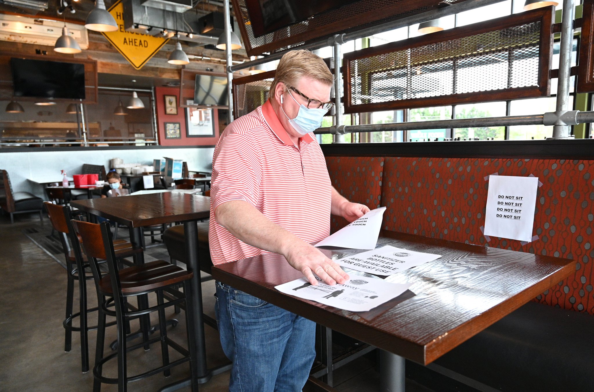 District manager Harry Decker sorts through signs on Saturday, April 25, 2020, for social distancing efforts as restaurant staff prepare to reopen the restaurant at Bad Daddy’s Burger Bar in Decatur. Gov. Brian Kemp announced that movie theaters and restaurant dining rooms can reopen Monday, April 27, following guidelines.