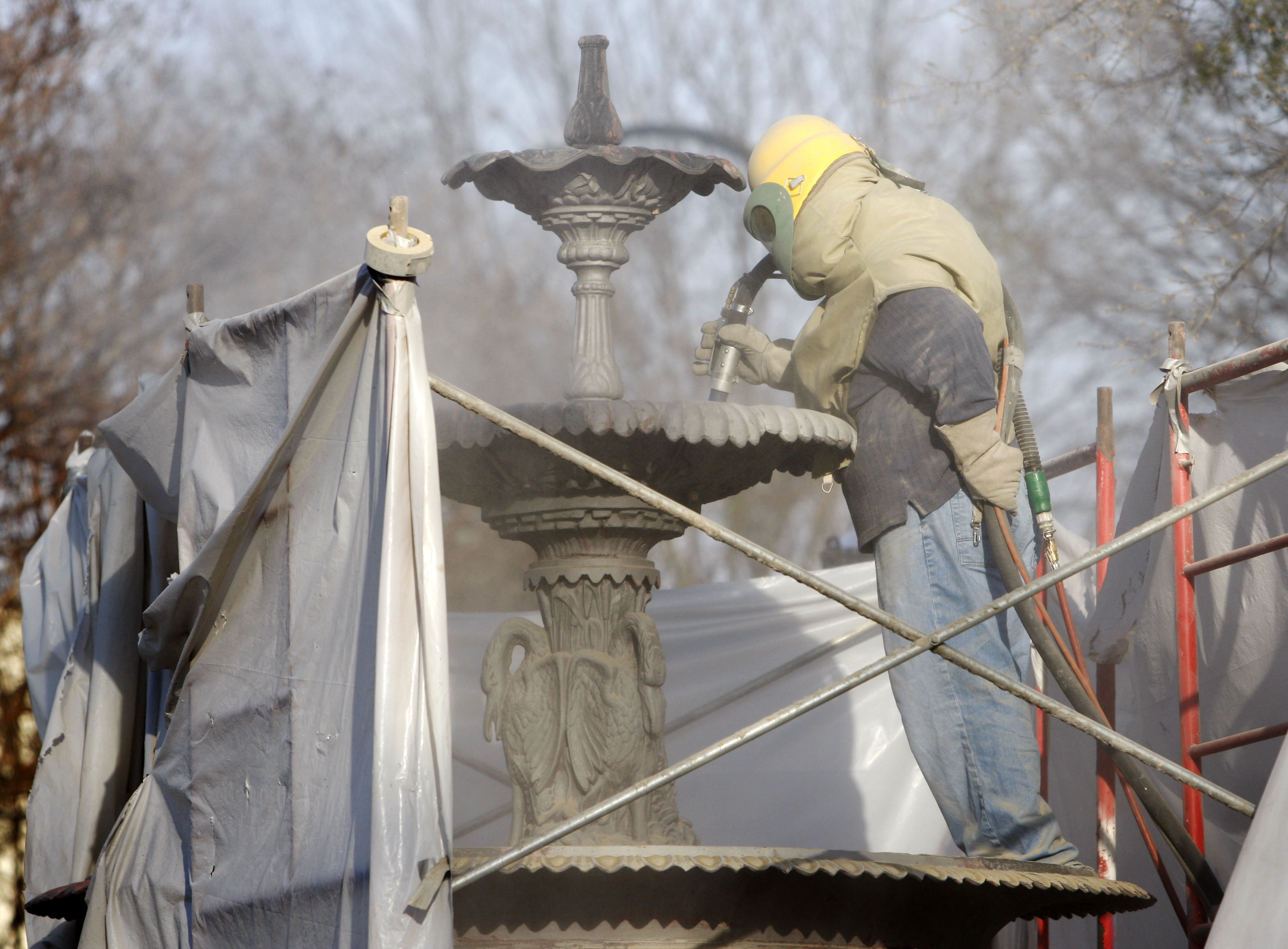 March 10, 2009: Remuijio Ortiz sandblasts the fountain in the middle of Marietta Square. Crews are stripping the new paint off to apply a new coat of epoxy primer and a coat of black epoxy paint with an antique finish. (Bob Andres/AJC)