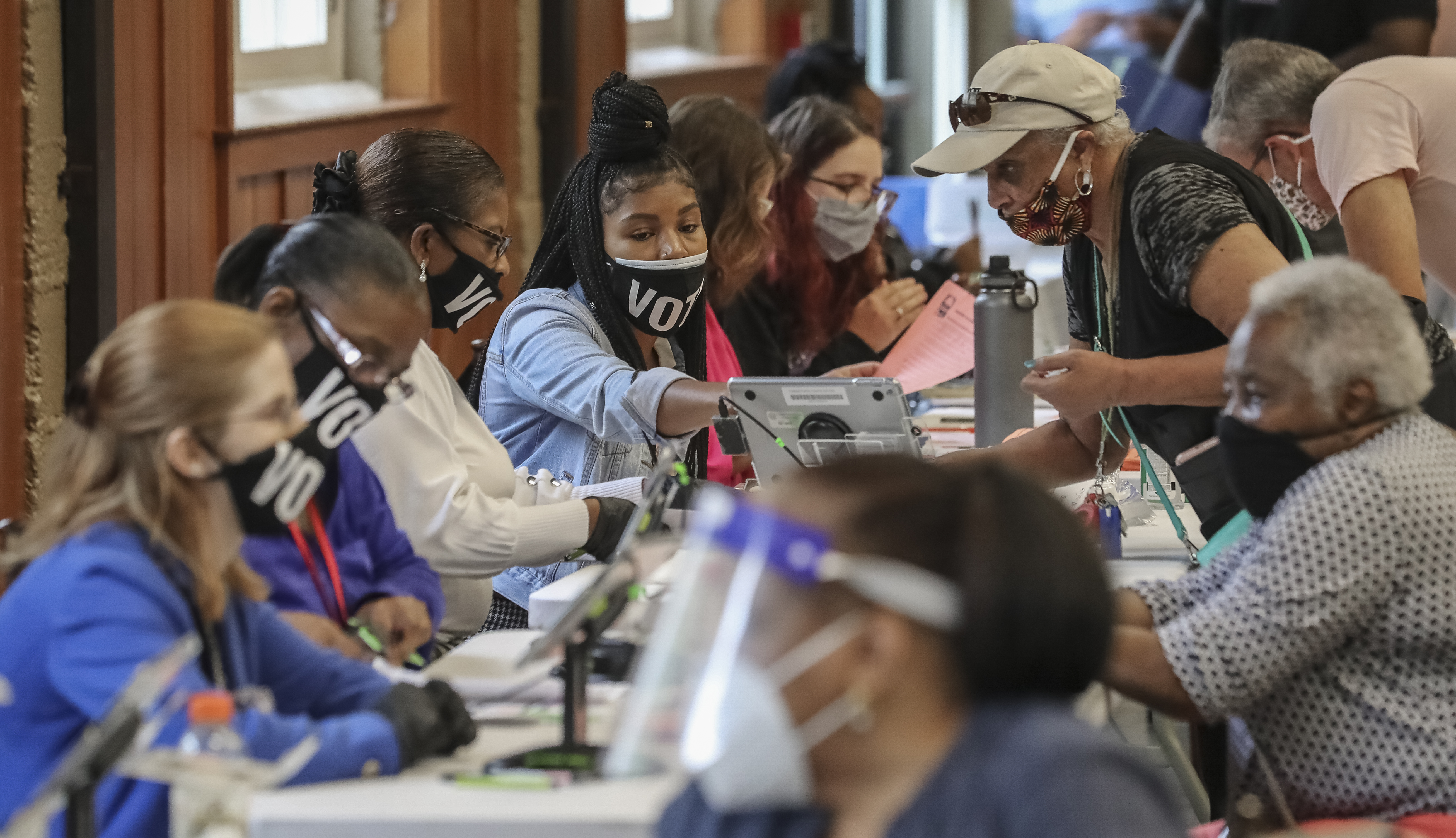 Poll workers prepare voters for the machines Tuesday at Magnolia Hall in Atlanta. Election officials said they learned lessons from the June 9 primary to avoid the kind of extreme lines that some voters encountered then. JOHN SPINK/JSPINK@AJC.COM