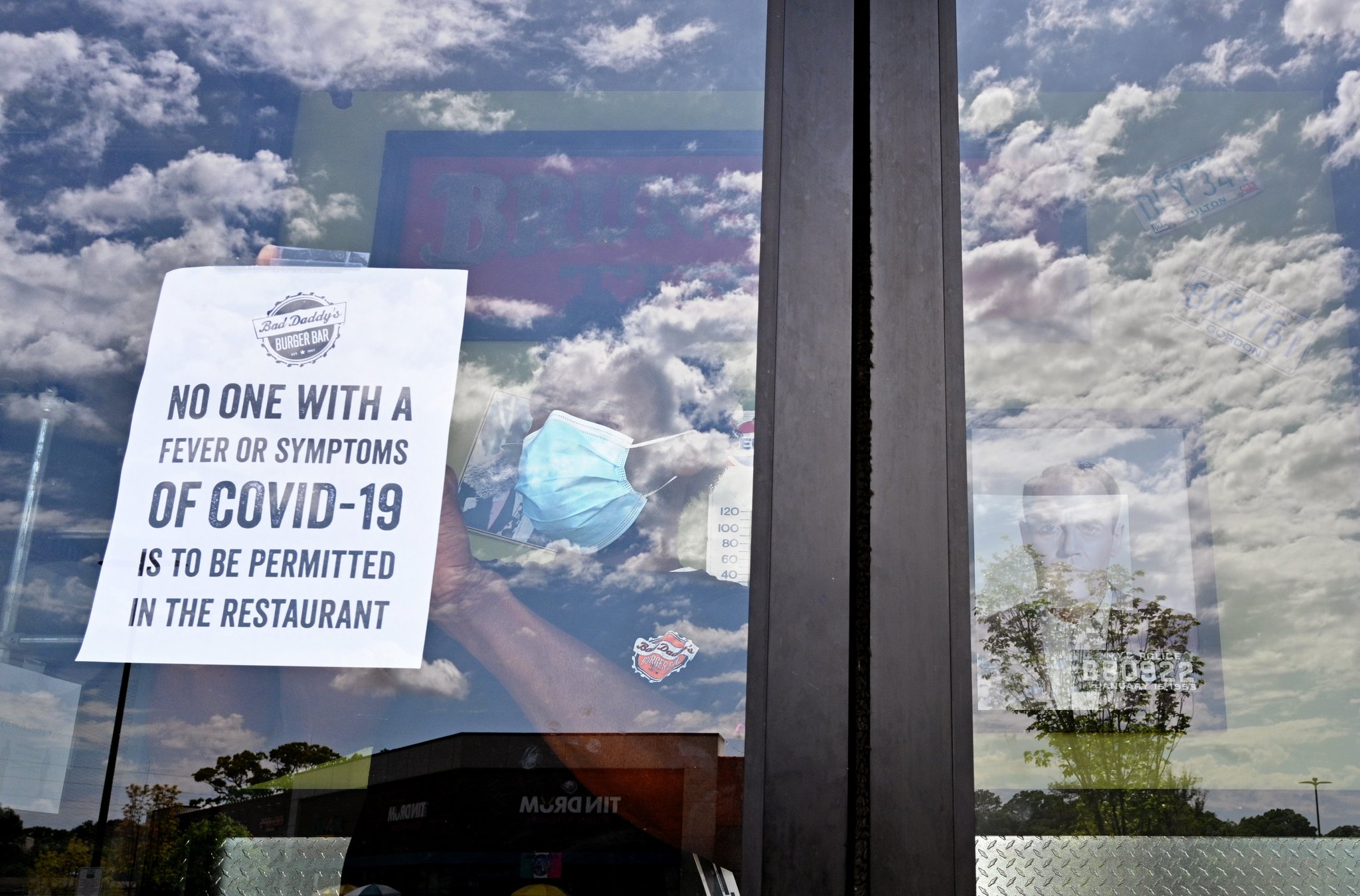 April 25, 2020 Decatur - Julian Douglas, employee, posts a warning sign at the main door as restaurant staff prepare to reopen the restaurant at Bad Daddy's Burger Bar in Decatur on Saturday, April 25, 2020. On Monday, Kemp announced shuttered businesses including barbershops, beauty and nail salons, spas, gyms and bowling alleys could reopen Friday. Movie theaters and restaurant dining rooms can reopen Monday. (Hyosub Shin / Hyosub.Shin@ajc.com)