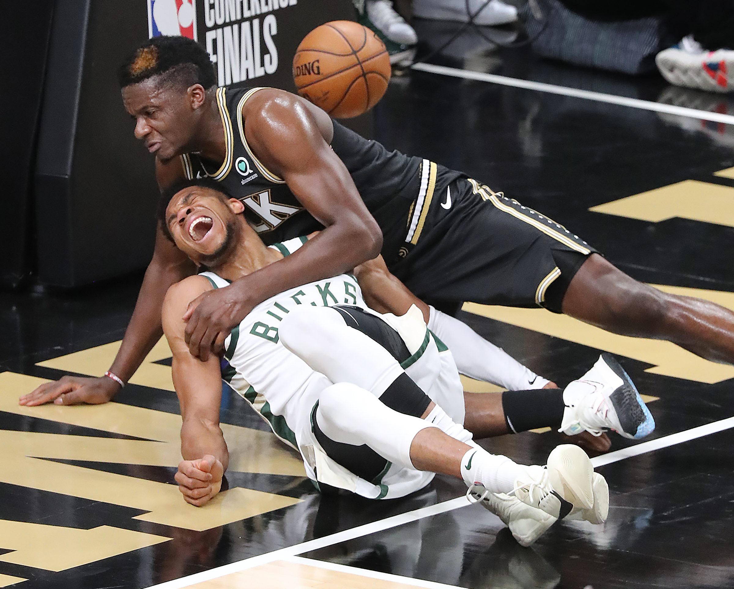 Hawks center Clint Capela (right) and Milwaukee Bucks forward Giannis Antetokounmpo fall after battling at the basket during the third quarter of Game 4 of the Eastern Conference finals Tuesday, June 29, 2021, at State Farm Arena in Atlanta. Antekounmpo left the game with an apparent knee injury. (Curtis Compton / Curtis.Compton@ajc.com)