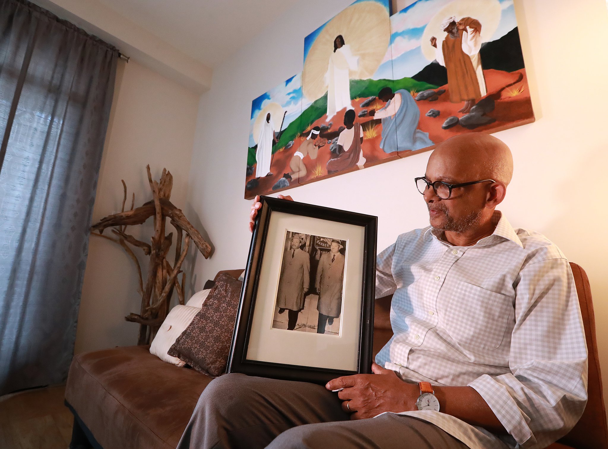 I. Logan Kearse holds a photograph of his dad Reverend Kearse with Martin Luther King Jr. taken in the 1950s during an interview at his residence beneath one of his paintings, this one depicting the Mount of Transfiguration on Tuesday, June 4, 2019, in Decatur.