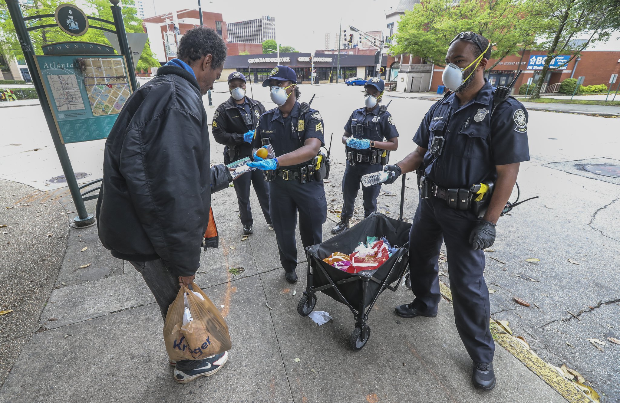 Atlanta Police Department officers distribute masks to the homeless at Hurt Park downtown on Friday, April 24, 2020.
