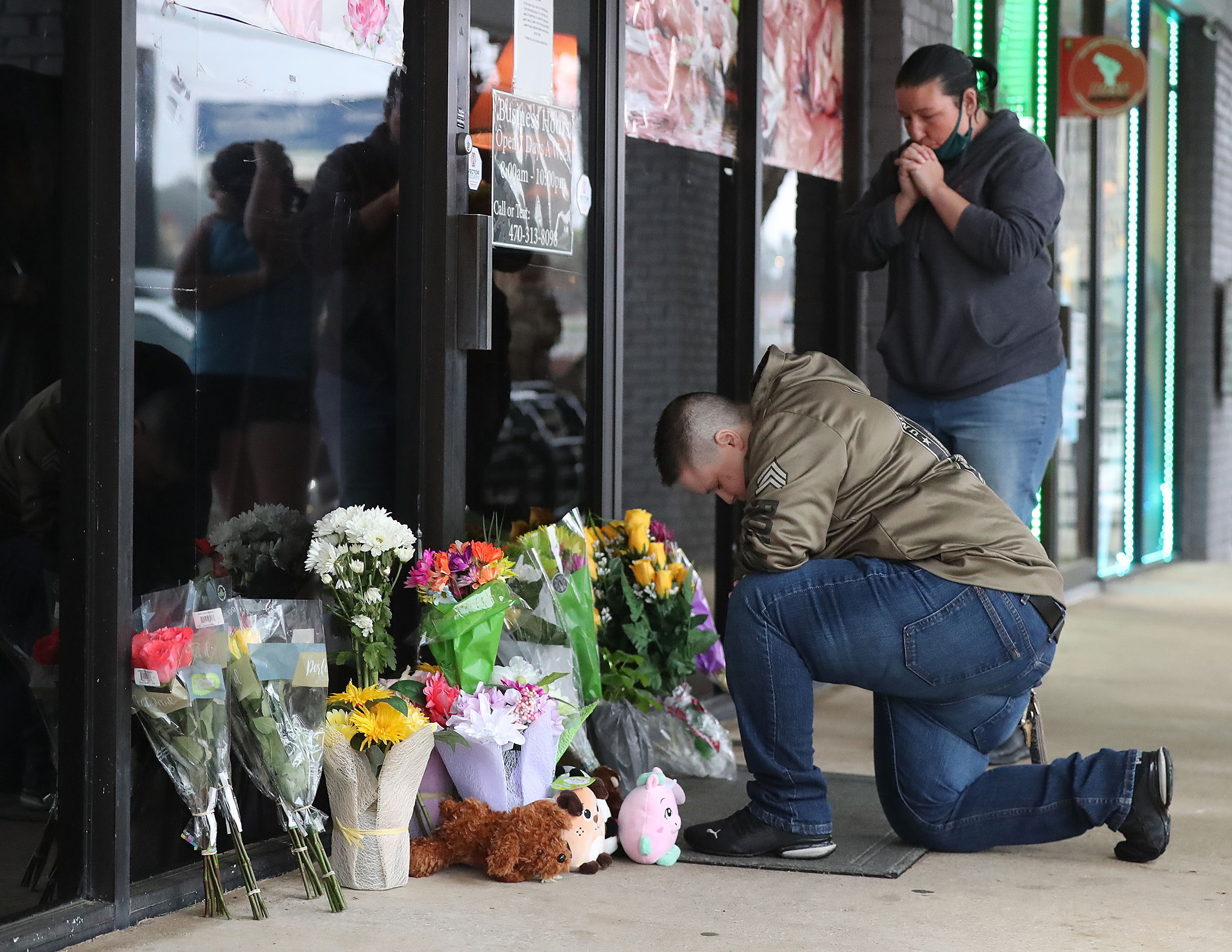 031721 Acworth: U.S. Army veteran Latrelle Rolling (left) and Jessica Lang (right) both pause to pray after dropping off flowers at Youngs Asian Massage on Wednesday, March 17, 2021, in Acworth. At least eight people were found dead at three different spas in the Atlanta area Tuesday by suspected killer Robert Aaron Long. “Curtis Compton / Curtis.Compton@ajc.com”