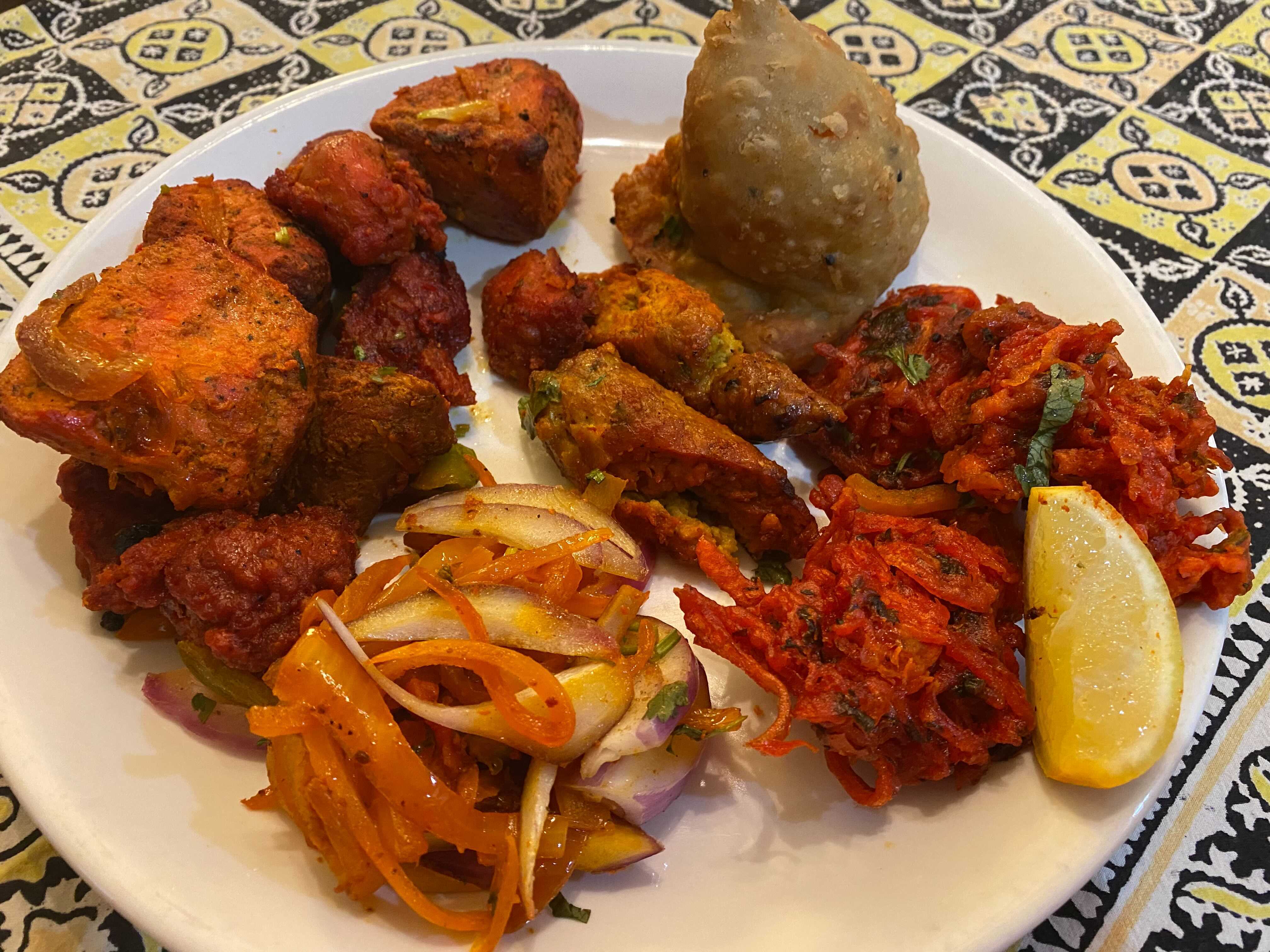 The tandoori roti is a hefty sampler of tandoori-grilled meats, plus onion pakoras and a vegetable or chicken samosa. Ligaya Figueras/ligaya.figueras@ajc.com
