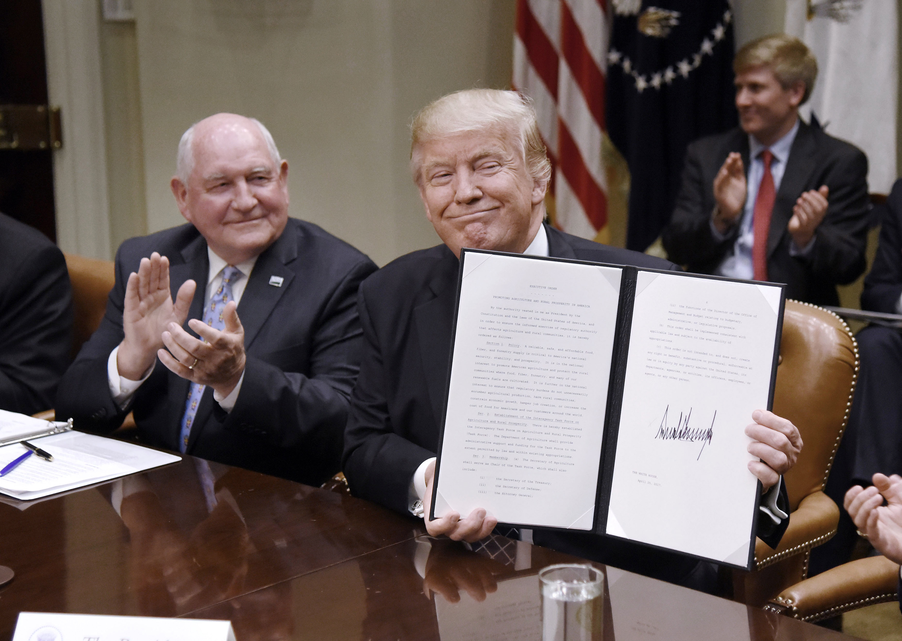 U.S. President Donald Trump signs the Executive Order Promoting Agriculture and Rural Prosperity in America as Agriculture Secretary Sonny Perdue looks on during a meeting with farmers on Tuesday, April 25, 2017, in the Roosevelt Room of the White House in Washington, D.C. (Olivier Douliery/Abaca Press/TNS)