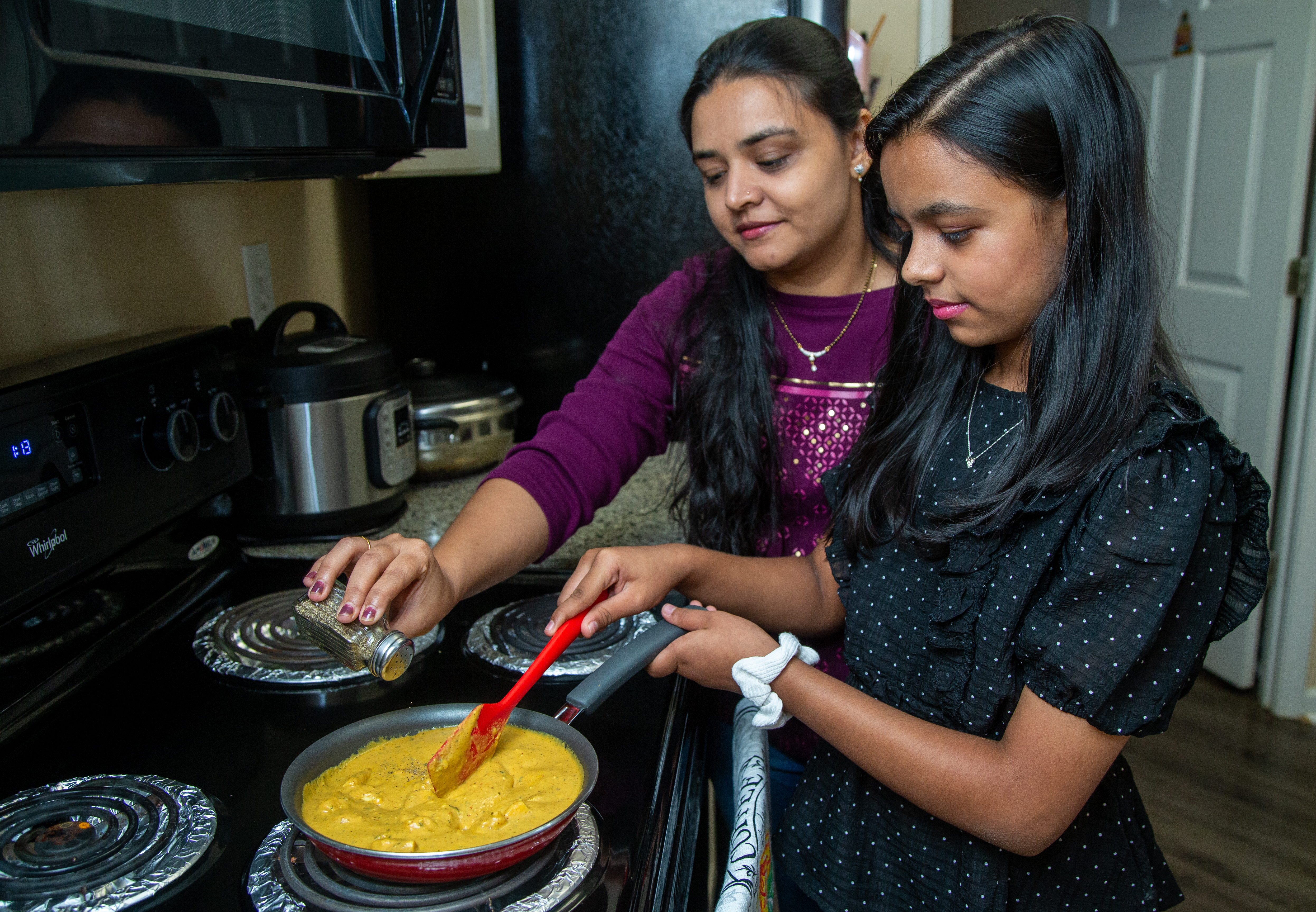 Aesha Bhatt (right) cooks with her mother, Hita, in their Johns Creek home.
PHIL SKINNER FOR THE ATLANTA JOURNAL-CONSTITUTION.
