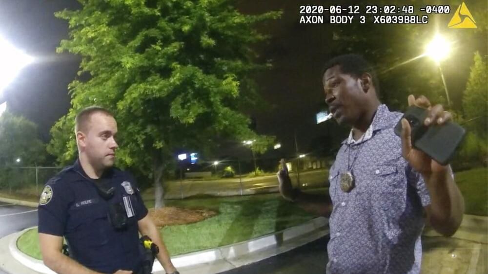 Garrett Rolfe, left, talking to Rashard Brooks in the parking lot of Wendy's moments before Brooks was shot and killed by Rolfe.