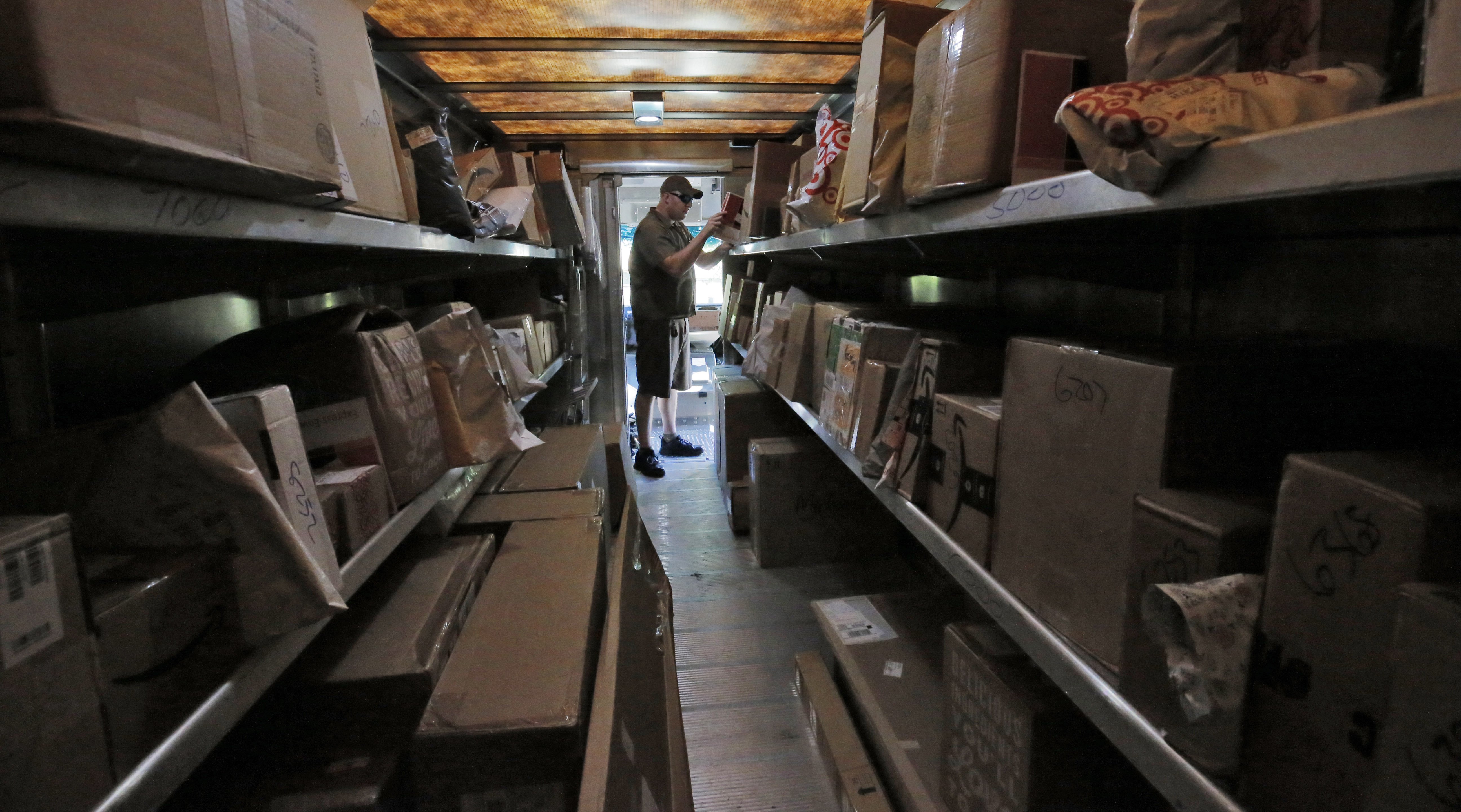 7/26/17 - Roswell, GA - In this view from the back of his truck, driver Dan Partyka's first priority is to deliver his overnight packages. As more people buy more goods online, the rapid and unrelenting expansion of e-commerce is causing real challenges for UPS. It costs more to deliver items to individual doorsteps instead of delivering a whole pallet full of goods to stores. BOB ANDRES /BANDRES@AJC.COM