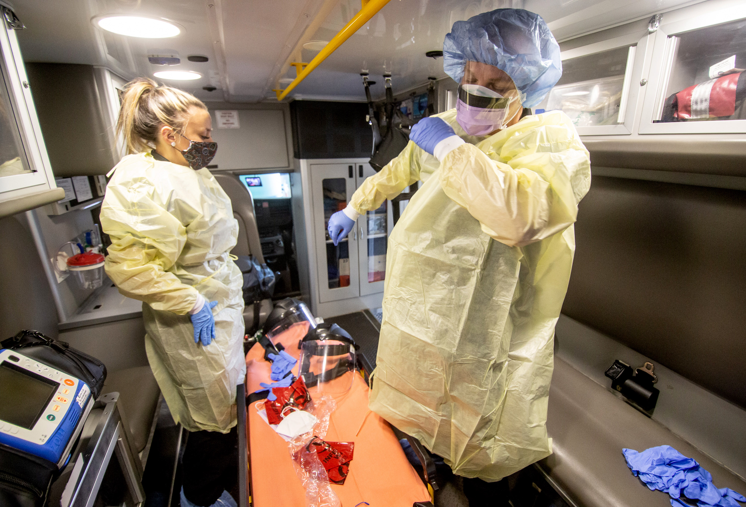 EMT Maci Williams, left, and Paramedic Christopher Kozinski demonstrate how they put on their personal protective equipment before every call at the Central EMS office in Roswell July 16, 2020. (STEVE SCHAEFER FOR THE ATLANTA JOURNAL-CONSTITUTION)