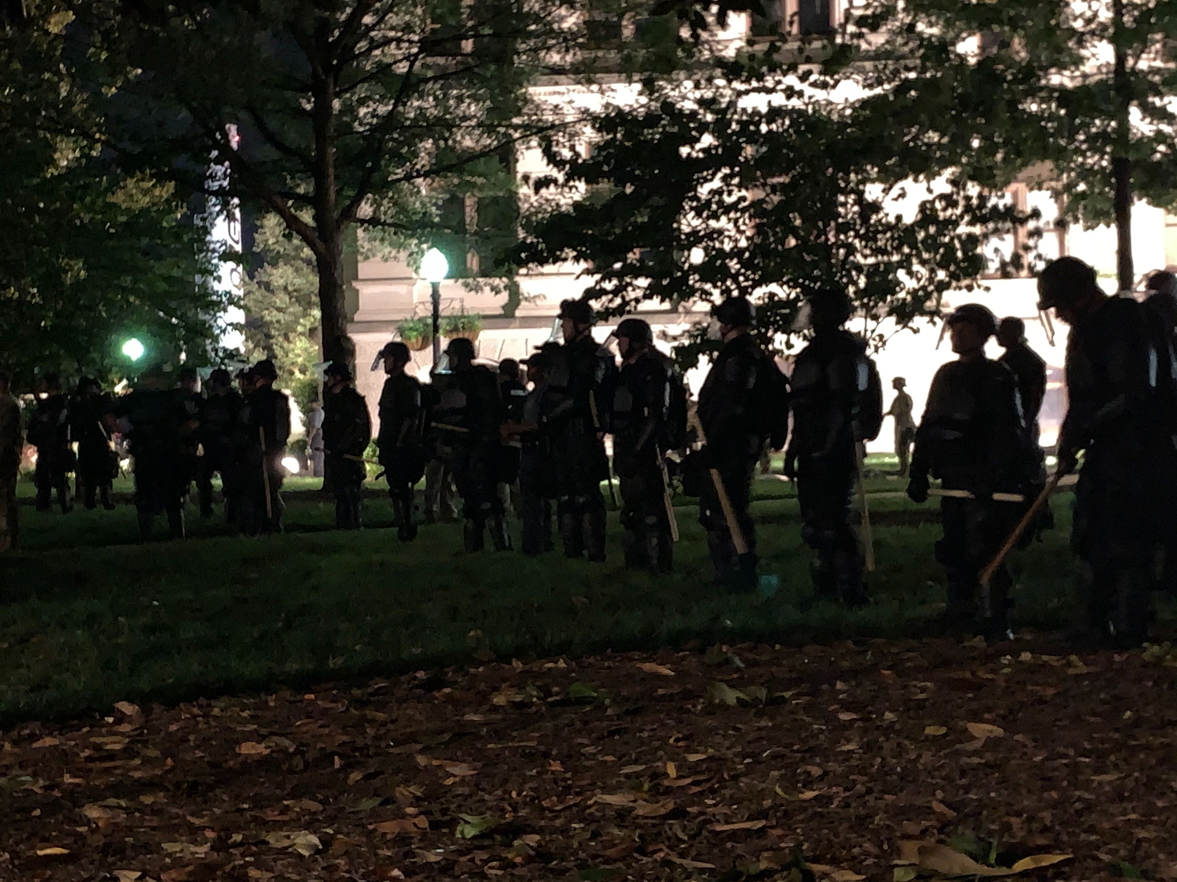 Law enforcement officers keep an eye on on a group of protesters late Saturday night at the Capitol. (Photo: Christian Boone / AJC)