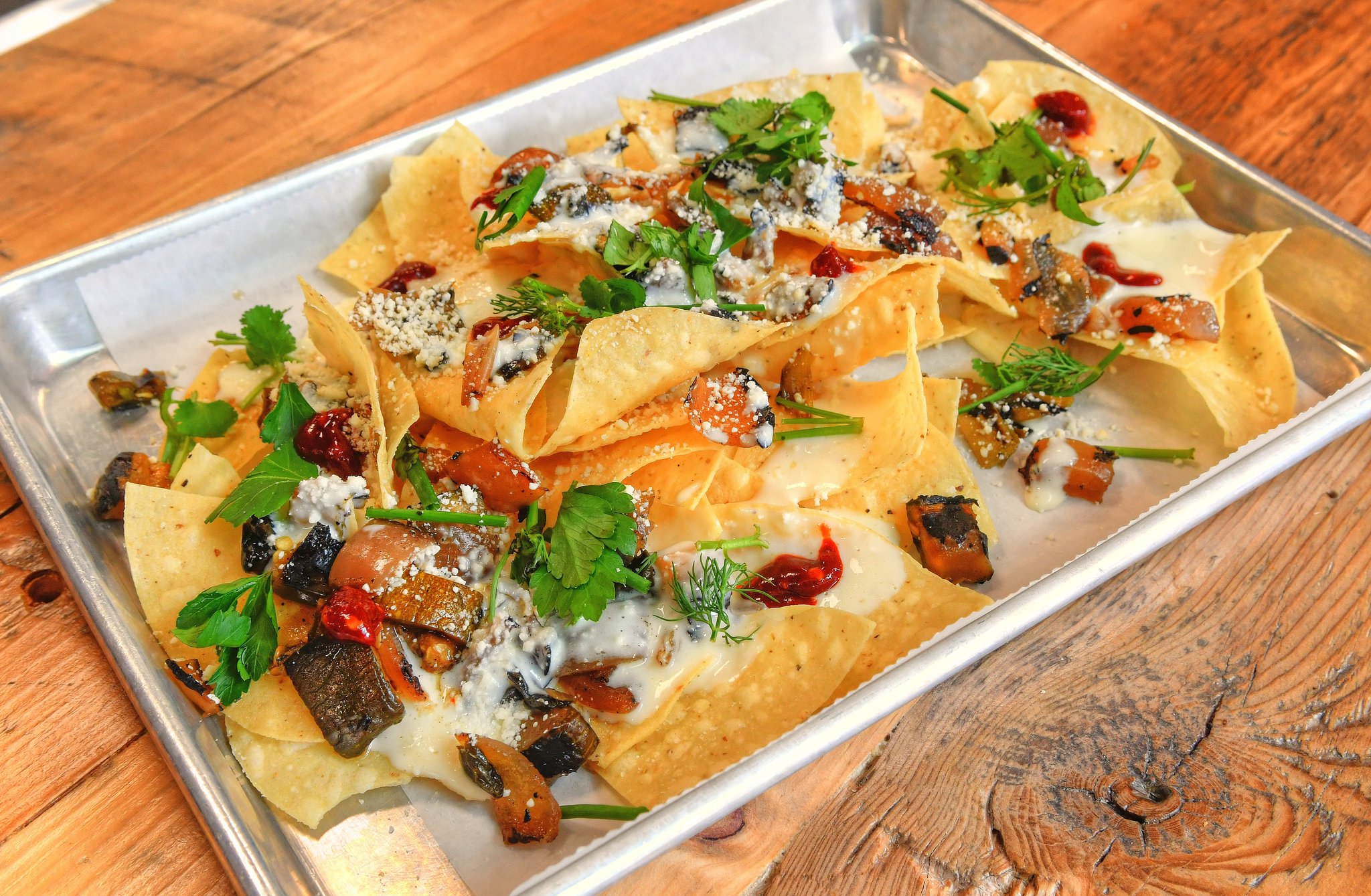 Macho Nachos, crunchy corn tortillas, queso sauce, charred veggies, cotija and herbs, plus add your favorite slow-cooked meat. CONTRIBUTED BY CHRIS HUNT PHOTOGRAPHY)