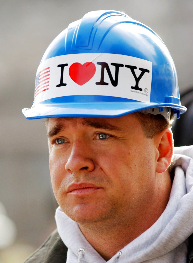 FILE - In this Oct. 11, 2001 file photo, with an "I Love NY" sticker on his hardhat, New York City firefighter Kevin Bohan pauses at a memorial service near ground zero in New York. Milton Glaser, the designer who created the "I (HEART) NY" logo and the famous Bob Dylan poster with psychedelic hair, has died. He died Friday, his 91st birthday.AP Photo/Stan Honda, pool, File)