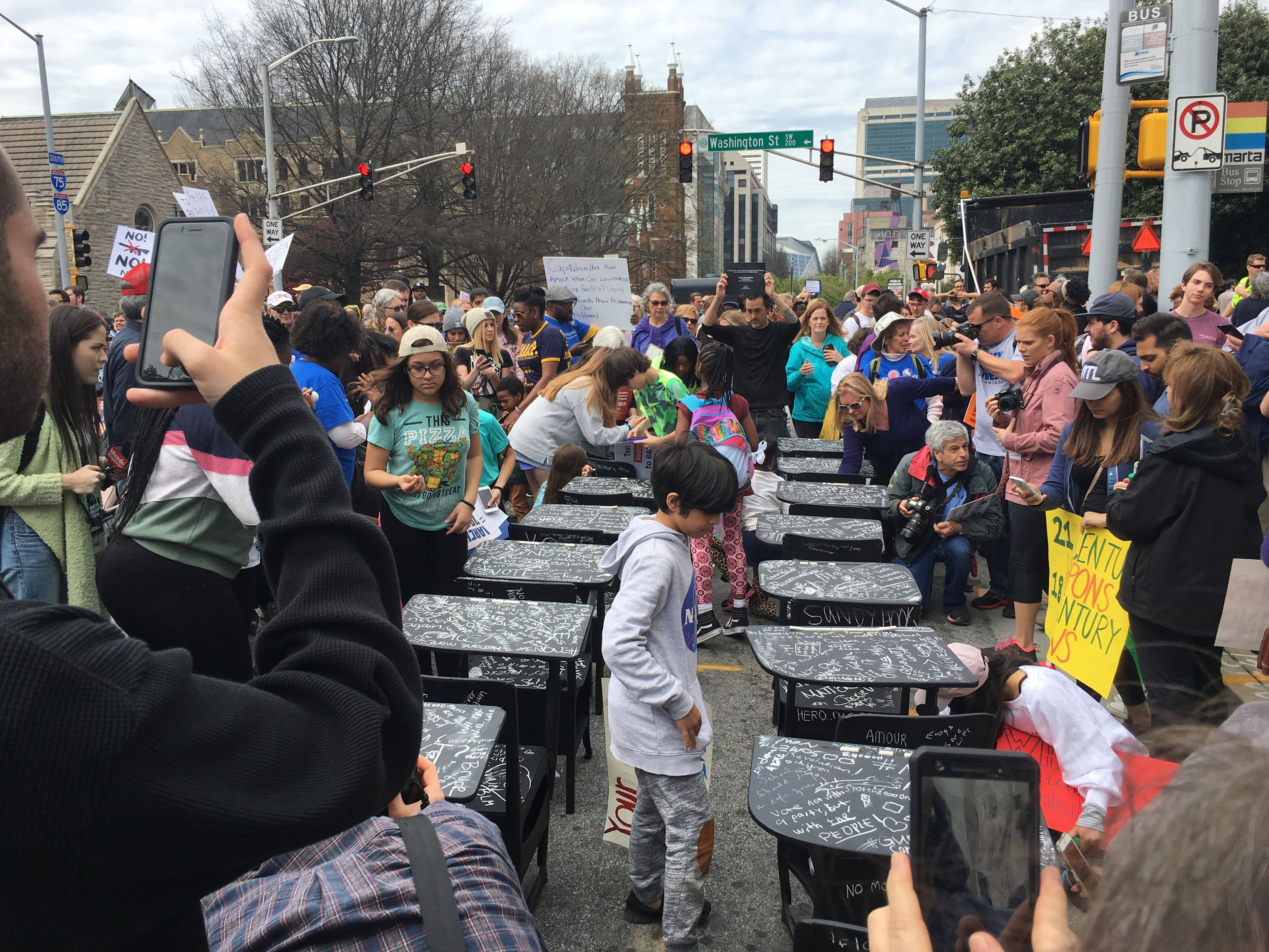 People examine Joseph Guay's exhibition on display in Atlanta: 14 school desks covered in black chalkboard paint in memory of the Parkland,Fla., student victims.