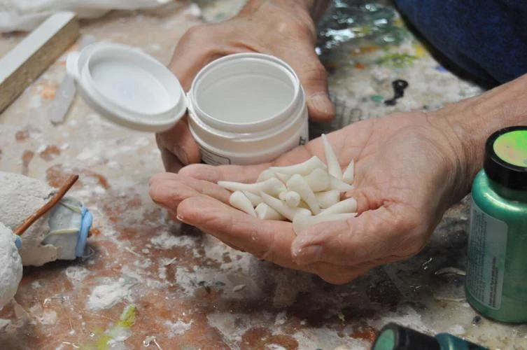 Fibus holds teeth he makes out of polymer clay for his whimsical sculptures of monsters and sea creatures. He keeps the teeth along with other sculpting materials in his workshop.