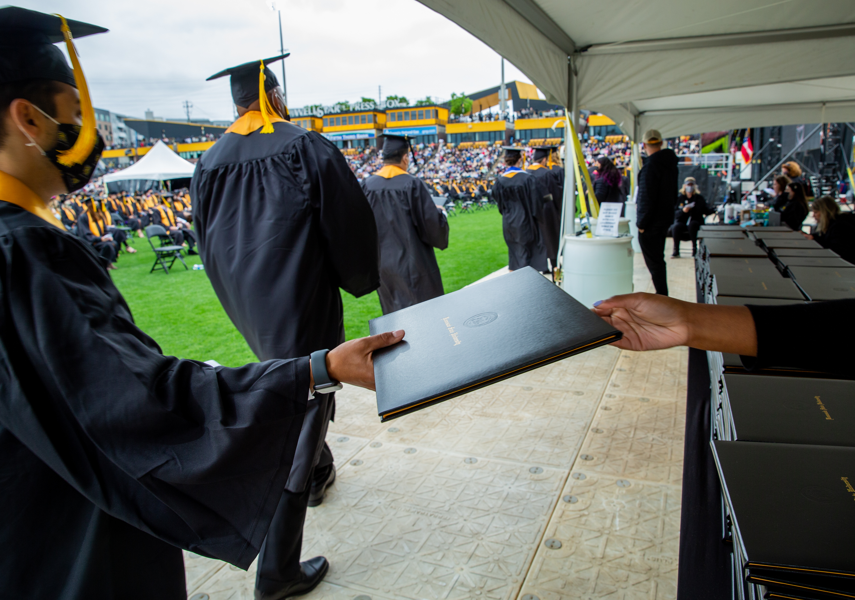 Kennesaw State University holds graduation Wednesday May 12, 2021 at the college’s stadium. Graduates are handed diplomas during the ceremony but will receive their specific diploma after graduation. (Jenni Girtman for The Atlanta Journal Constitution)
