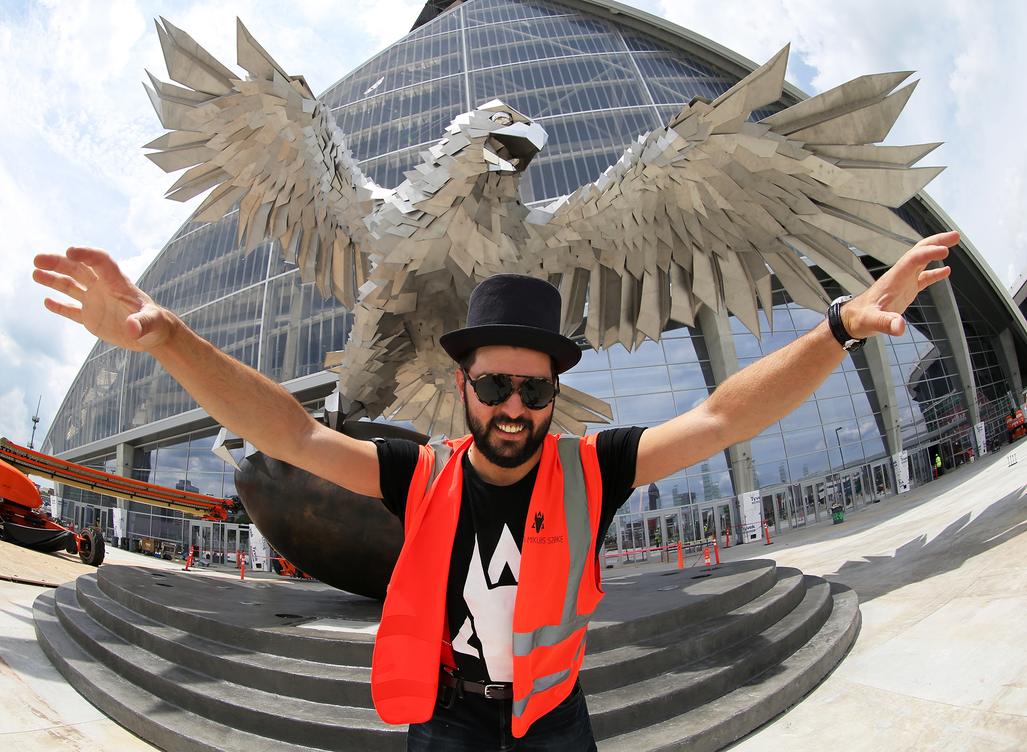 Artist Gabor MIklos Szoke strikes a pose with his stainless steel sculpture of a falcon that is 41.5 feet tall and has a wingspan of more than 64 feet during a tour of Mercedes-Benz Stadium on Thursday, June 1, 2017, in Atlanta. Curtis Compton/ccompton@ajc.com
