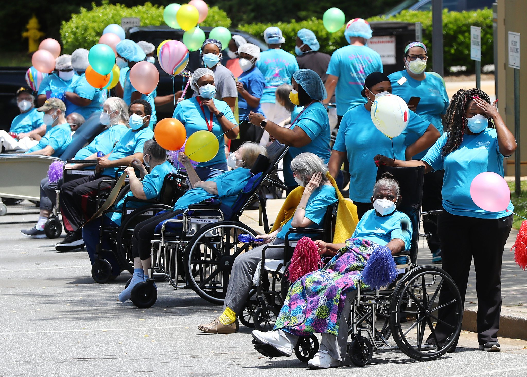 Residents and staff line the curb fin May for the start of a community parade celebrating residents who have survived COVID-19 at Westbury Medical Care & Rehab in Jackson. Family members and supporters decorated vehicles with signs and posters and for many it was the first opportunity to see their loved ones in months. Curtis CURTIS COMPTON / CCOMPTON@AJC.COM