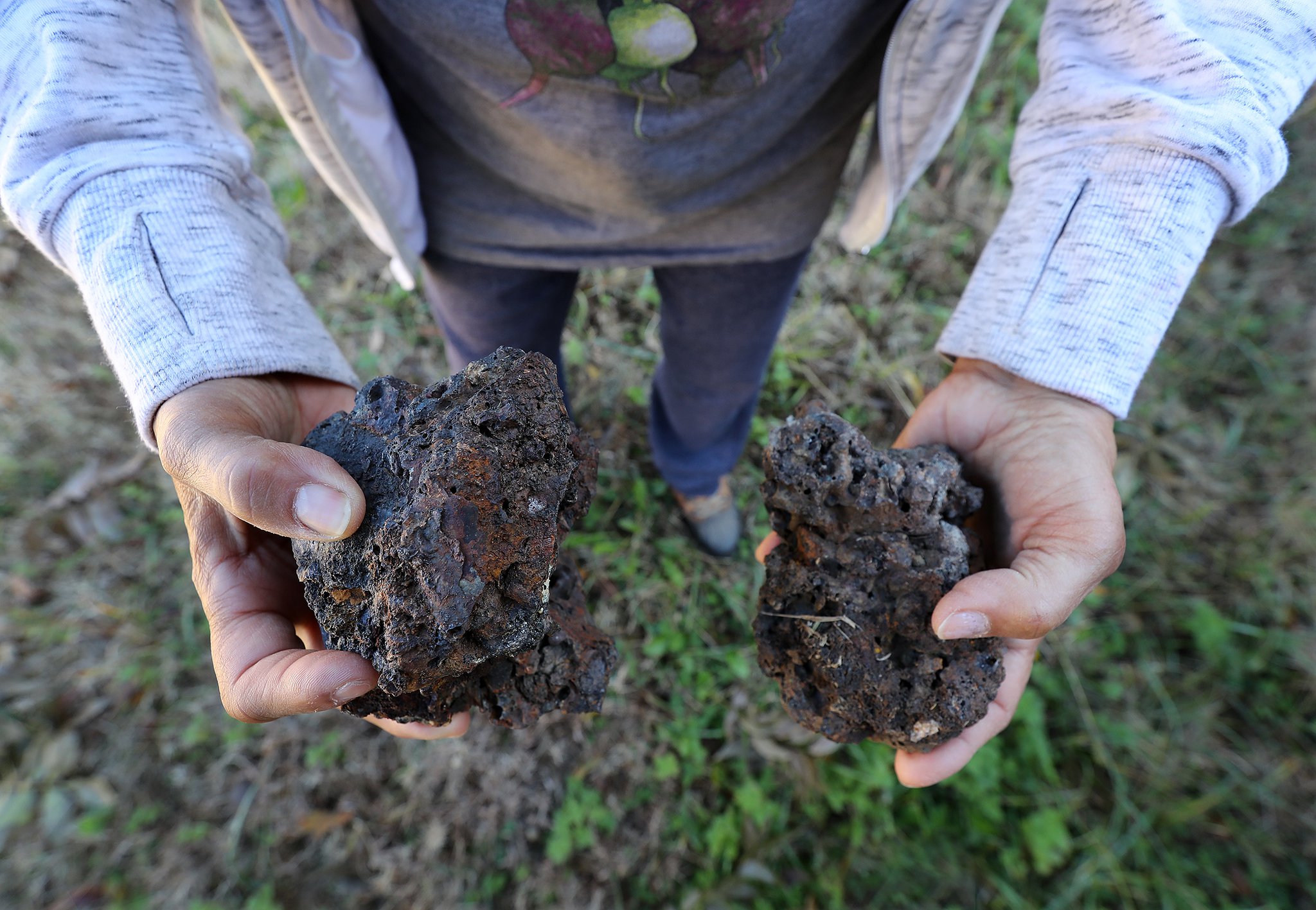 Rosario Hernandez shows off some of the chunks of slag, a byproduce of smelting, that she has found on the vacant lot next to her home near Mercedes-Benz Stadium on Monday, Nov. 25, 2019, in Atlanta. CURTIS COMPTON / CCOMPTON@AJC.COM