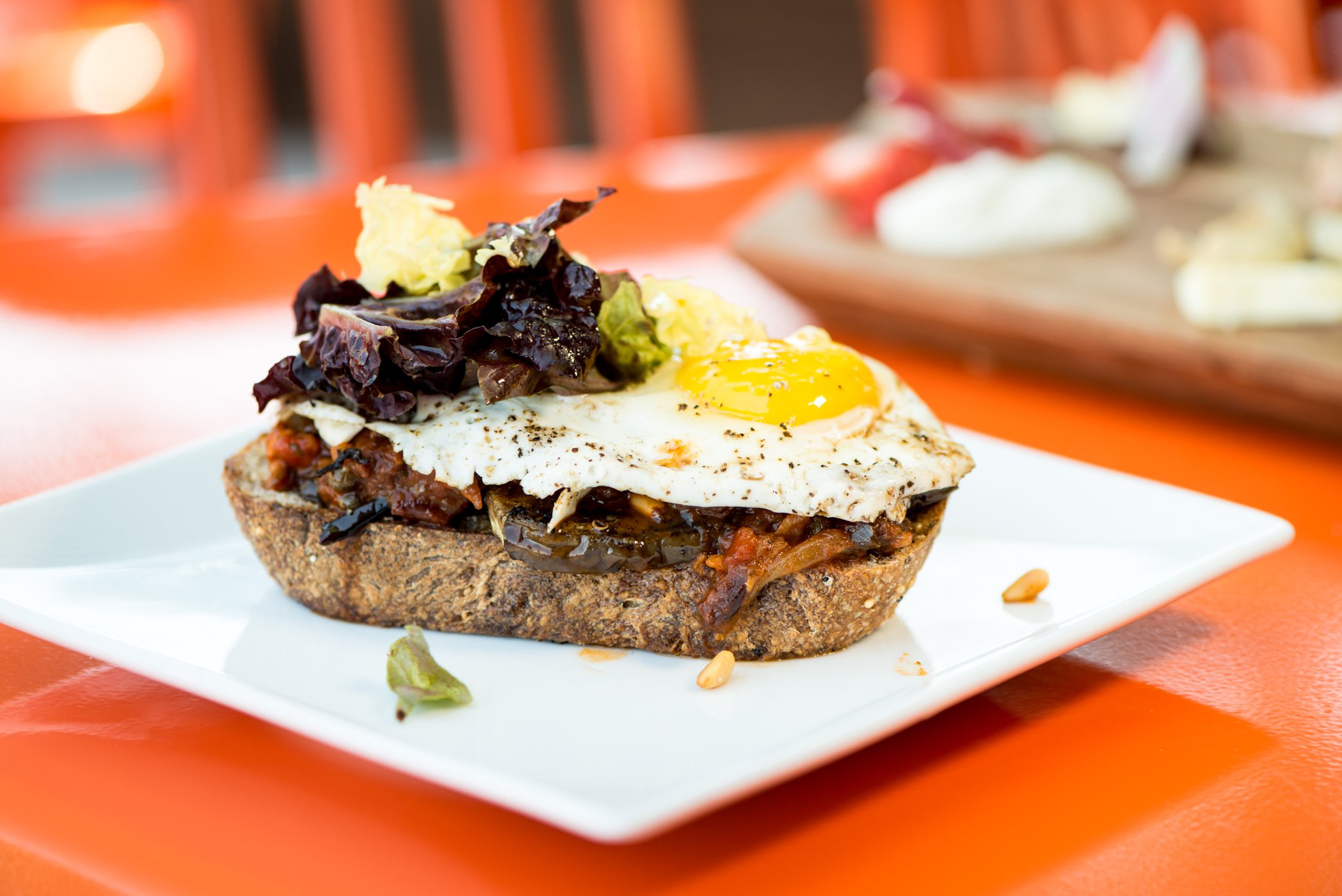 Eggplant Caponata with thickly sliced multigrain toast, greens, and a sunny egg. Photo credit- Mia Yakel.