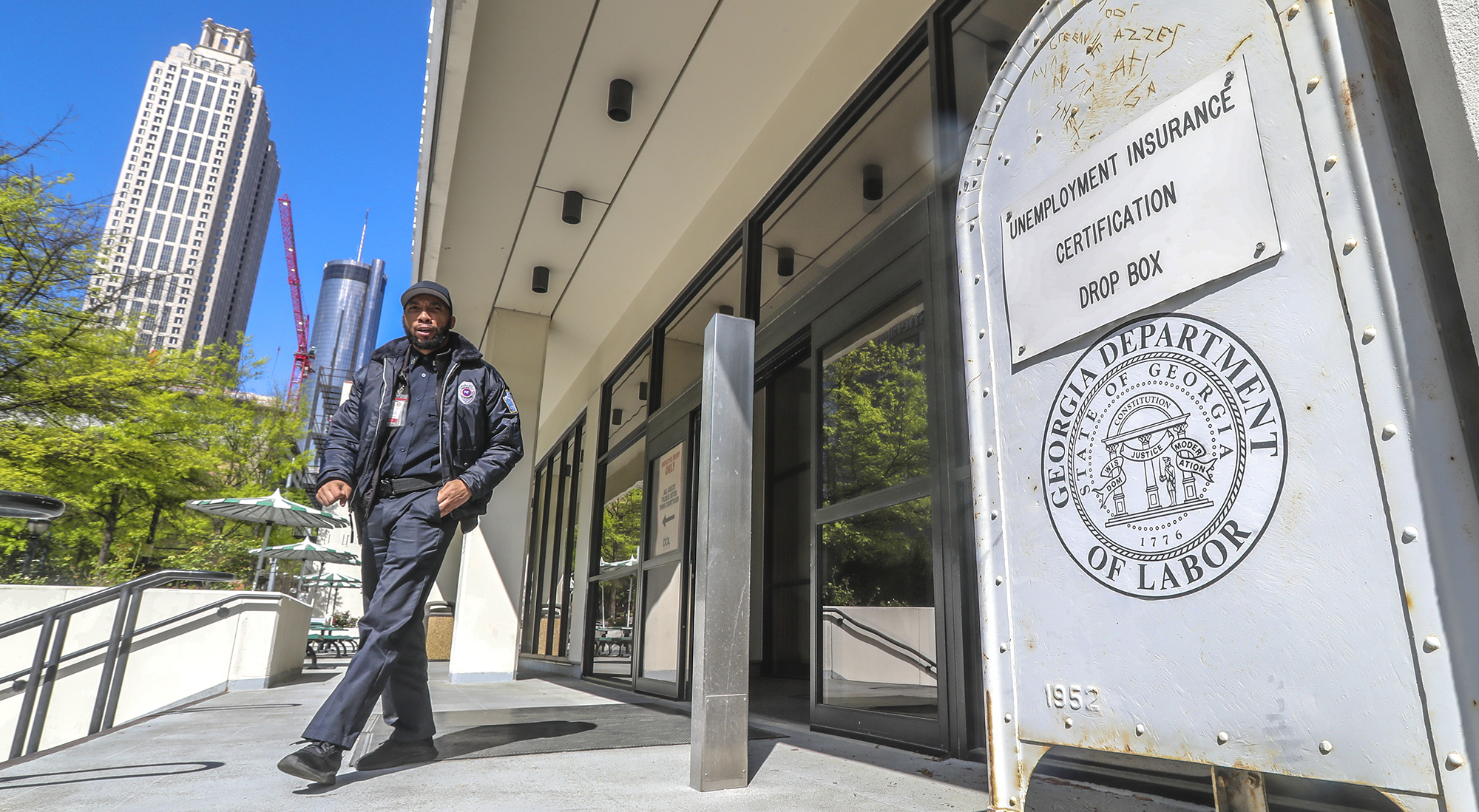 A security guard at the Georgia Department of Labor at 223 Courtland St. NE in Atlanta walks past the unemployment certification drop box in front of the office. Unemployment claims have skyrocketed since the COVID-19 pandemic has shut down businesses across the state and country. JOHN SPINK/JSPINK@AJC.COM