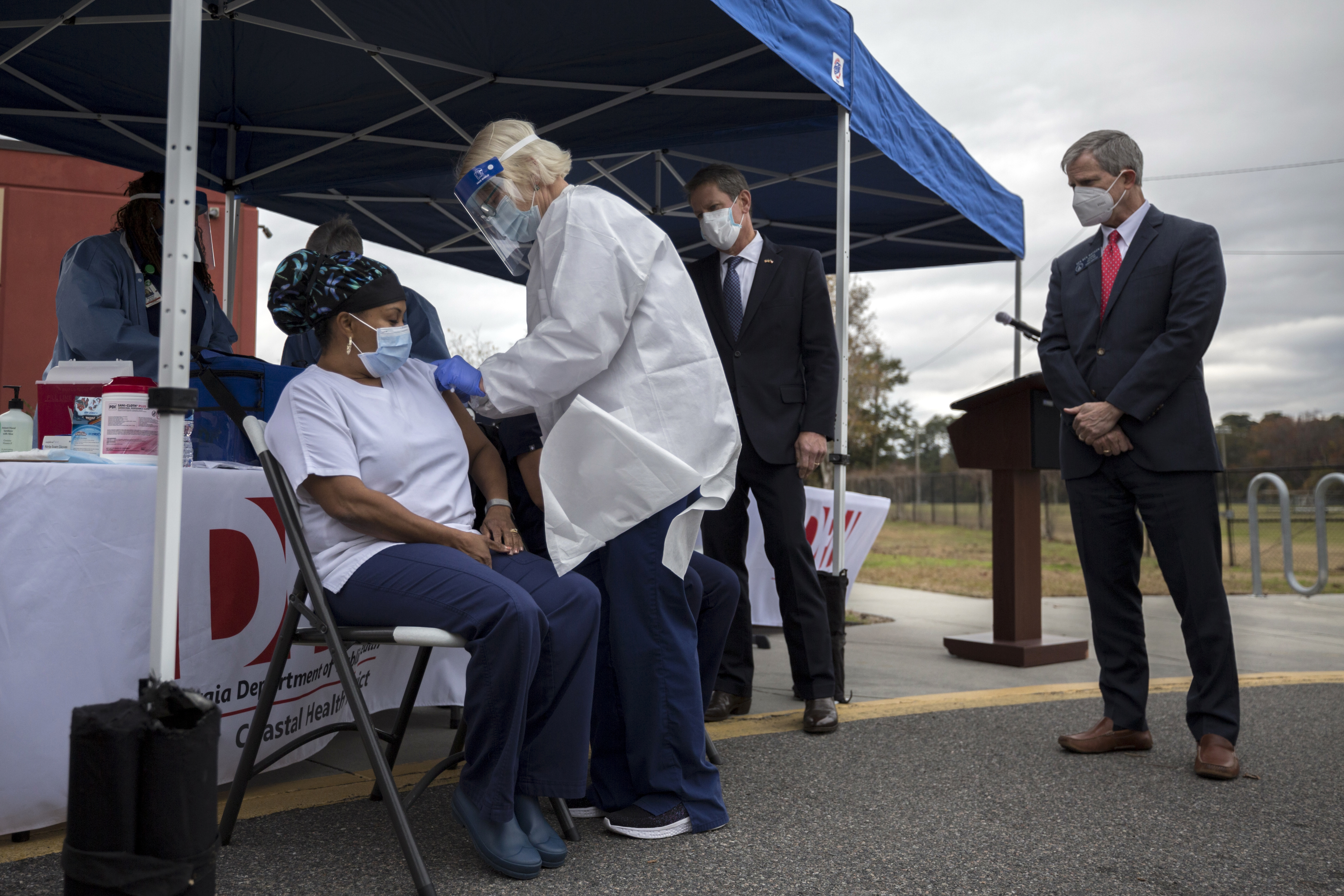 State Sen. Ben Watson, right, watches one of the first inoculations of the Pfizer-BioNTech COVID-19 vaccine given to healthcare workers in Savannah on Tuesday. (AJC Photo/Stephen B. Morton)